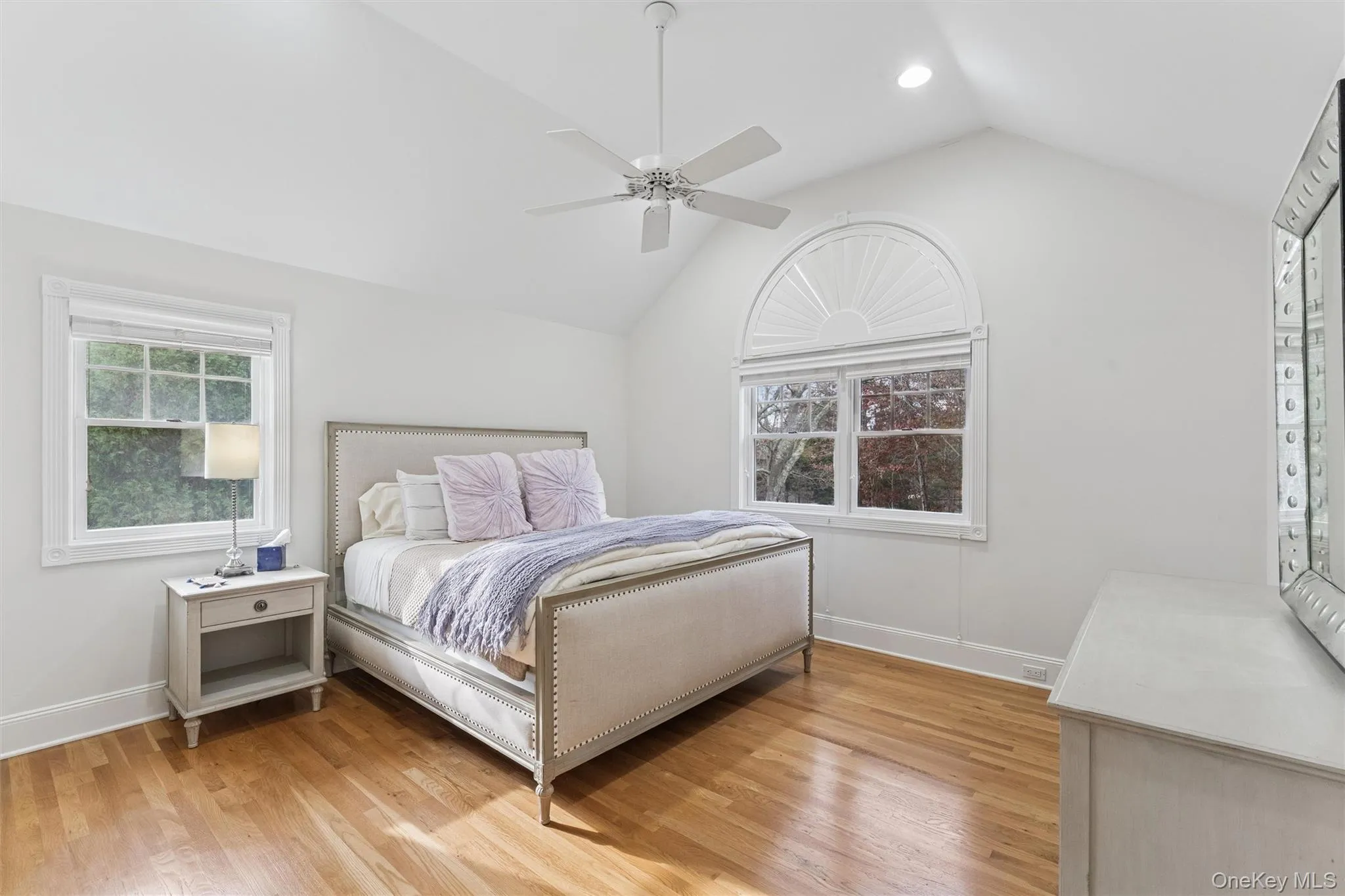 Bedroom with lofted ceiling, light wood-style floors, a ceiling fan, multiple windows, and recessed lighting Bedroom with lofted ceiling, light wood-style floors, a ceiling fan, multiple windows, and recessed lighting