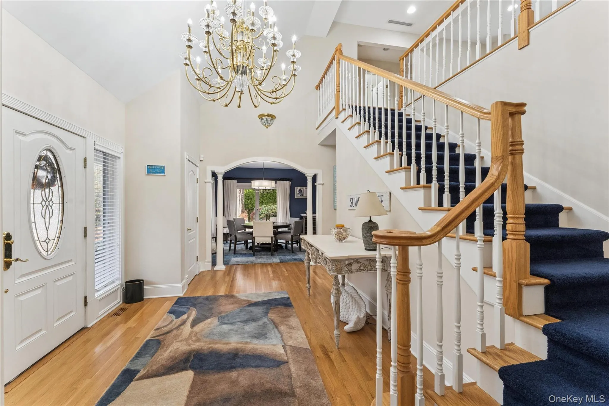 Foyer with a chandelier, arched walkways, light wood-style floors, and high vaulted ceiling Foyer with a chandelier, arched walkways, light wood-style floors, and high vaulted ceiling