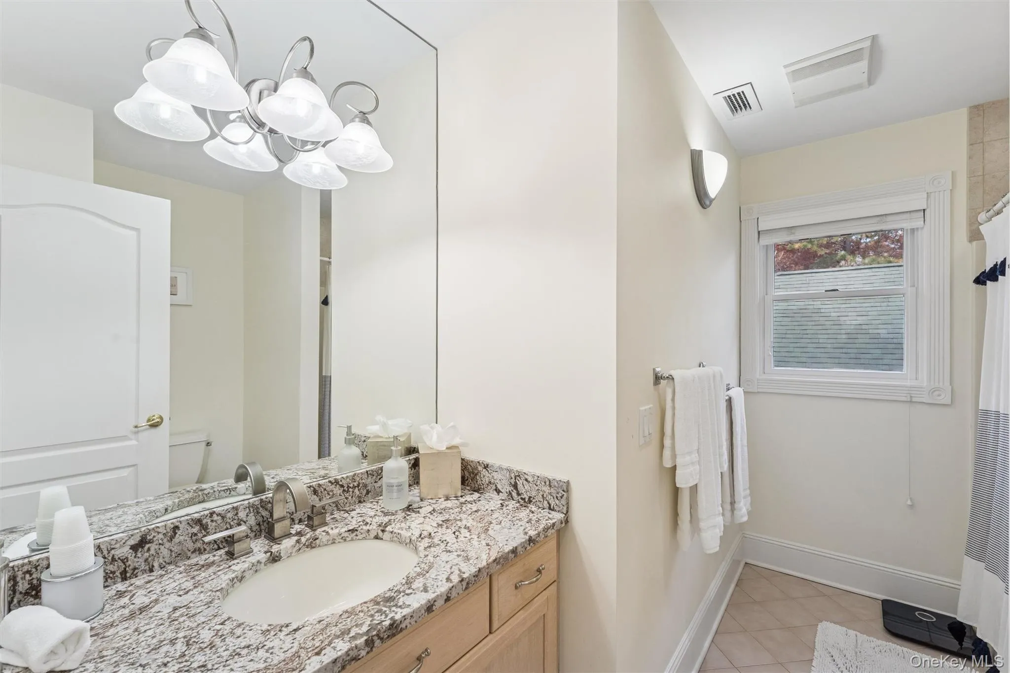 Full bath featuring vanity, light tile patterned floors, a chandelier, and a shower with curtain Full bath featuring vanity, light tile patterned floors, a chandelier, and a shower with curtain