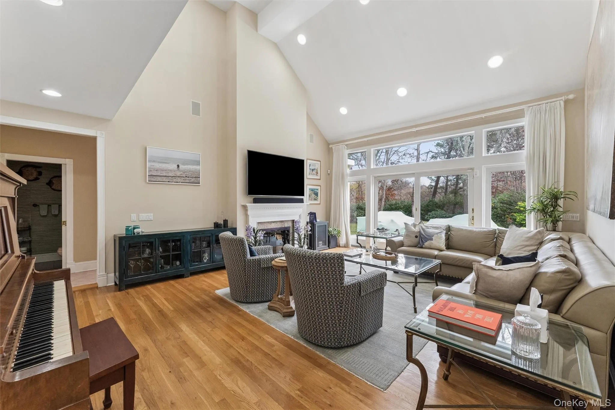 Living area featuring high vaulted ceiling, a fireplace, recessed lighting, and light wood-type flooring Living area featuring high vaulted ceiling, a fireplace, recessed lighting, and light wood-type flooring