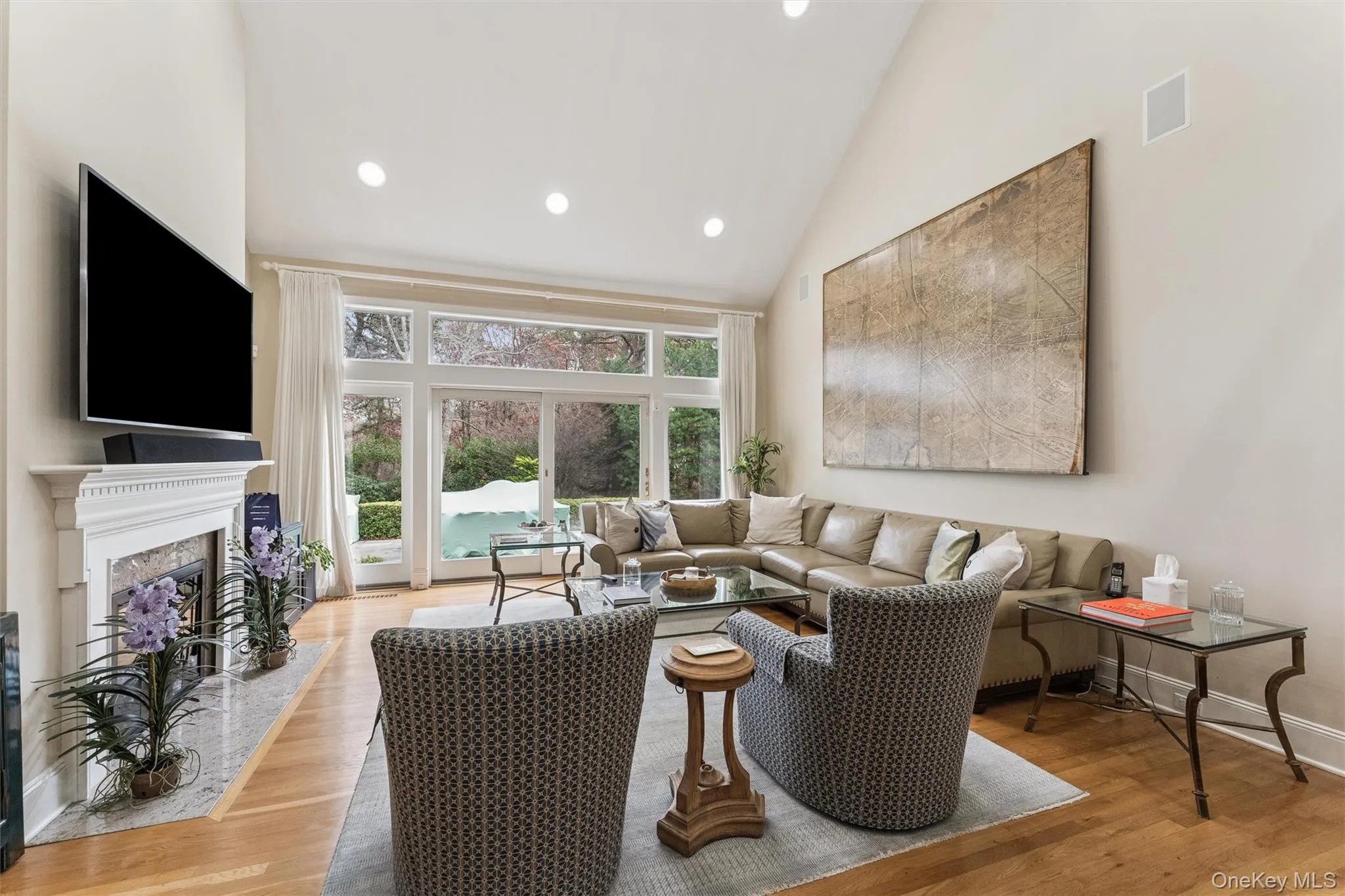 Living room featuring high vaulted ceiling, light wood-style floors, recessed lighting, and a high end fireplace Living room featuring high vaulted ceiling, light wood-style floors, recessed lighting, and a high end fireplace