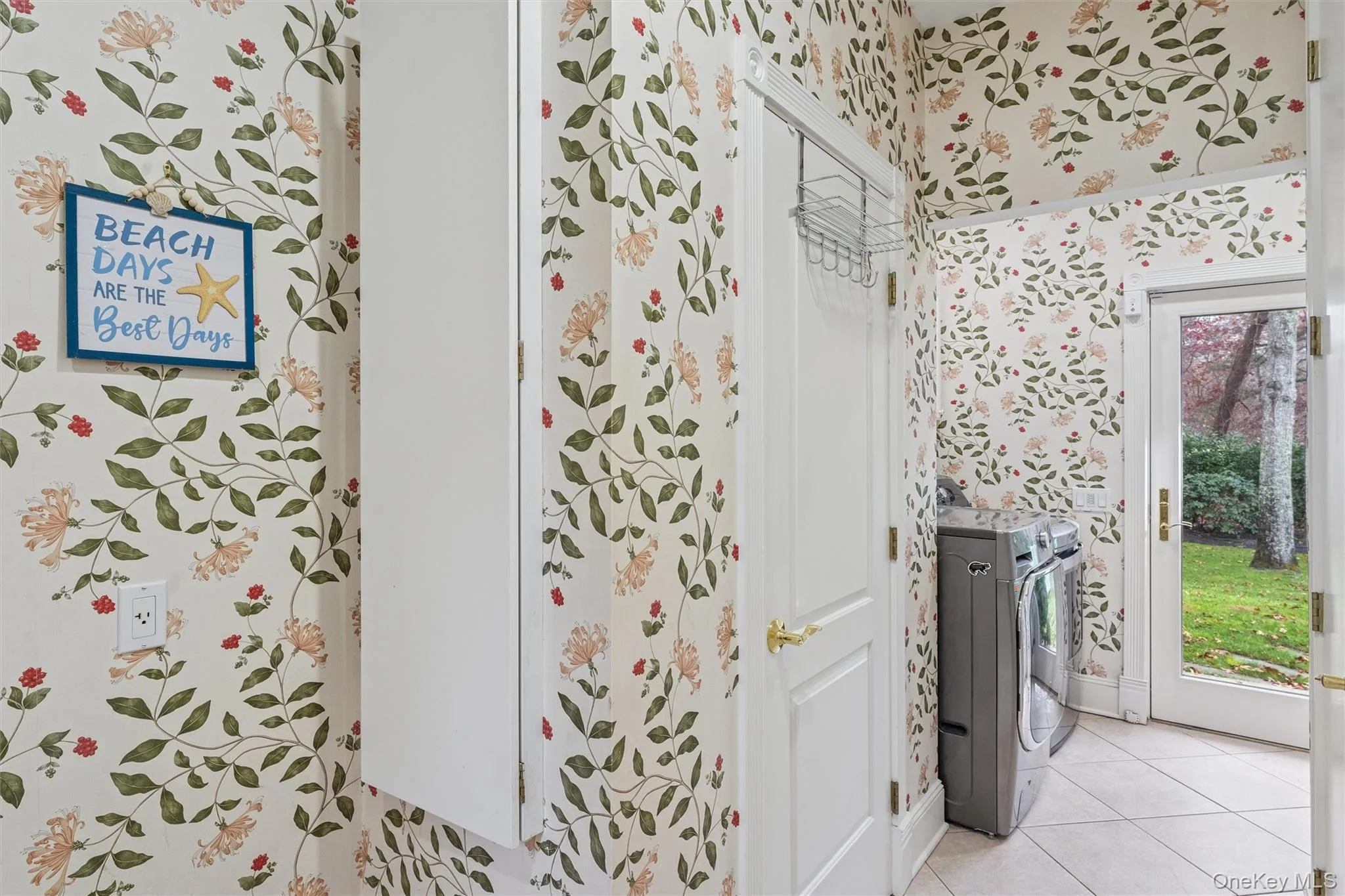 Bathroom featuring wallpapered walls, light tile patterned floors, and washing machine and dryer Bathroom featuring wallpapered walls, light tile patterned floors, and washing machine and dryer