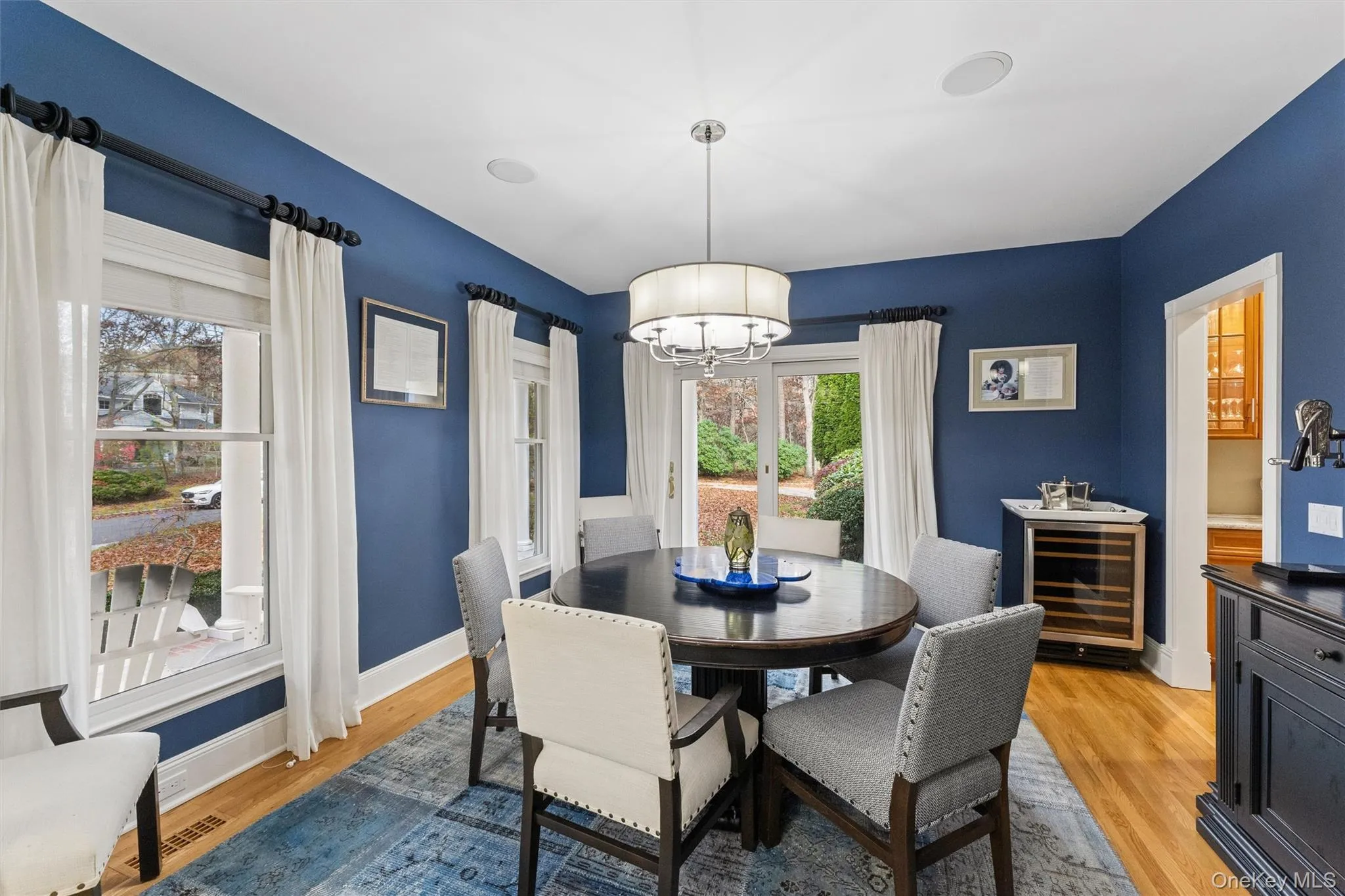 Dining room featuring light wood-style floors, beverage cooler, and a chandelier Dining room featuring light wood-style floors, beverage cooler, and a chandelier