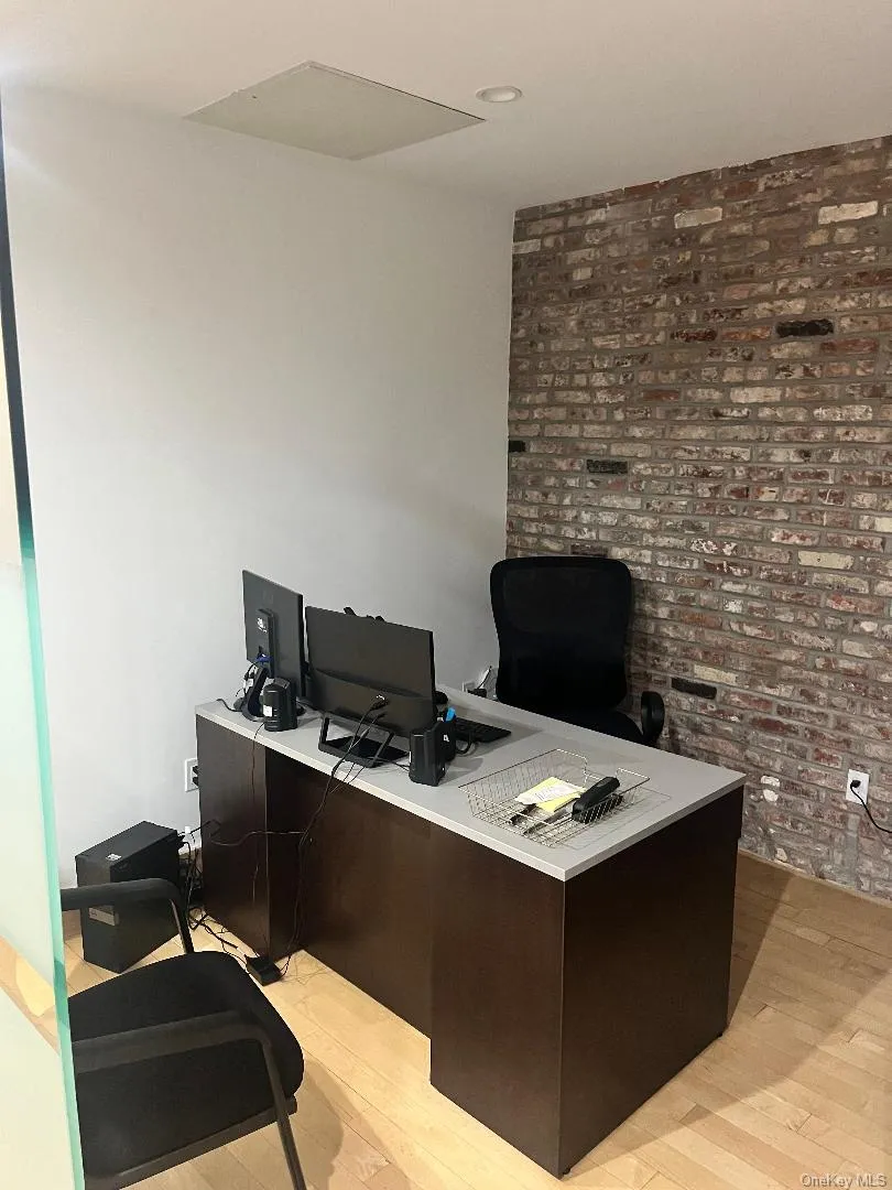 Office space featuring brick wall and light wood-style floors Office space featuring brick wall and light wood-style floors