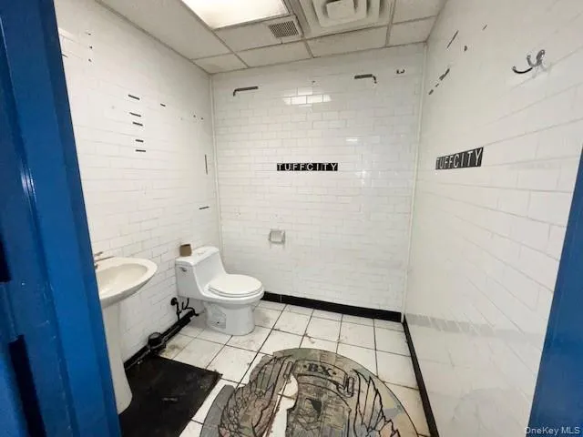 Half bath featuring toilet and tile walls Half bath featuring toilet and tile walls
