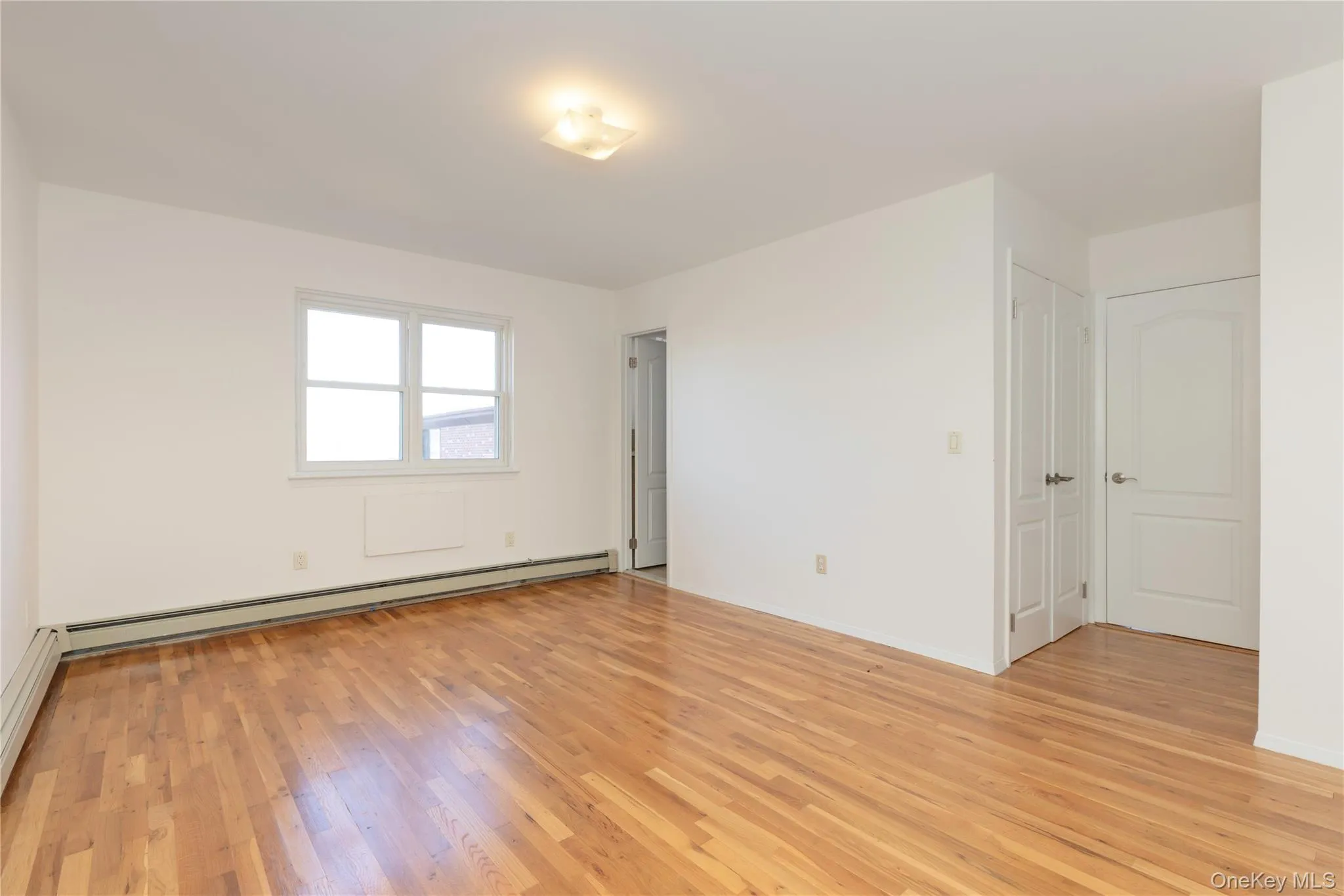 Primary bedroom featuring light wood finished floors and baseboard heating Primary bedroom featuring light wood finished floors and baseboard heating
