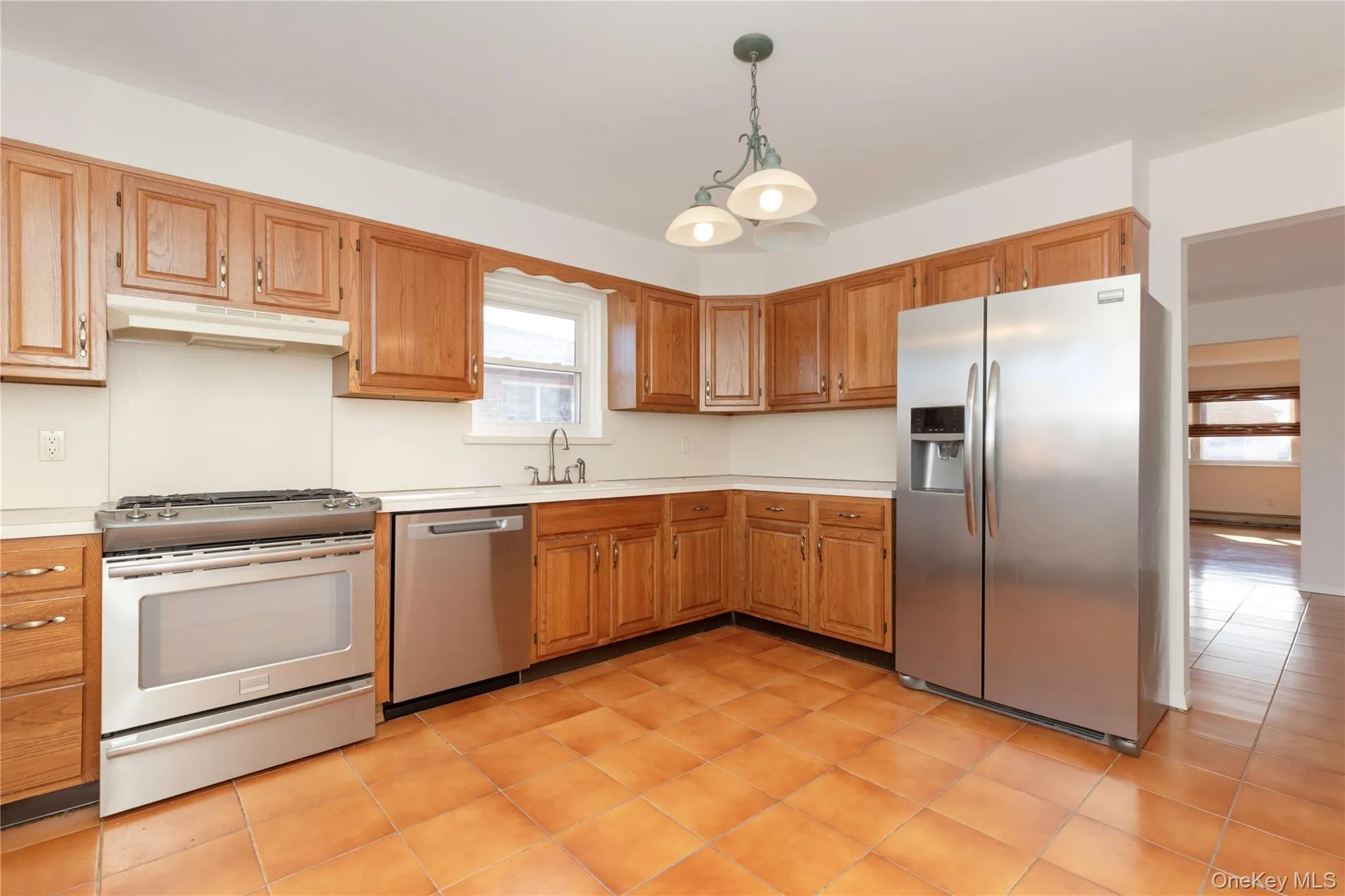 Eat-in-Kitchen with stainless steel appliances, pendant lighting, light countertops, under cabinet range hood, and light tile patterned floors Eat-in-Kitchen with stainless steel appliances, pendant lighting, light countertops, under cabinet range hood, and light tile patterned floors