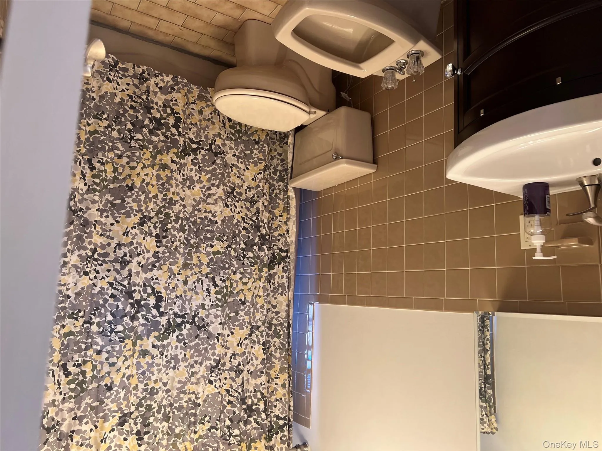 Bathroom featuring tile walls, vanity, a shower with curtain, tile patterned flooring, and a bidet Bathroom featuring tile walls, vanity, a shower with curtain, tile patterned flooring, and a bidet