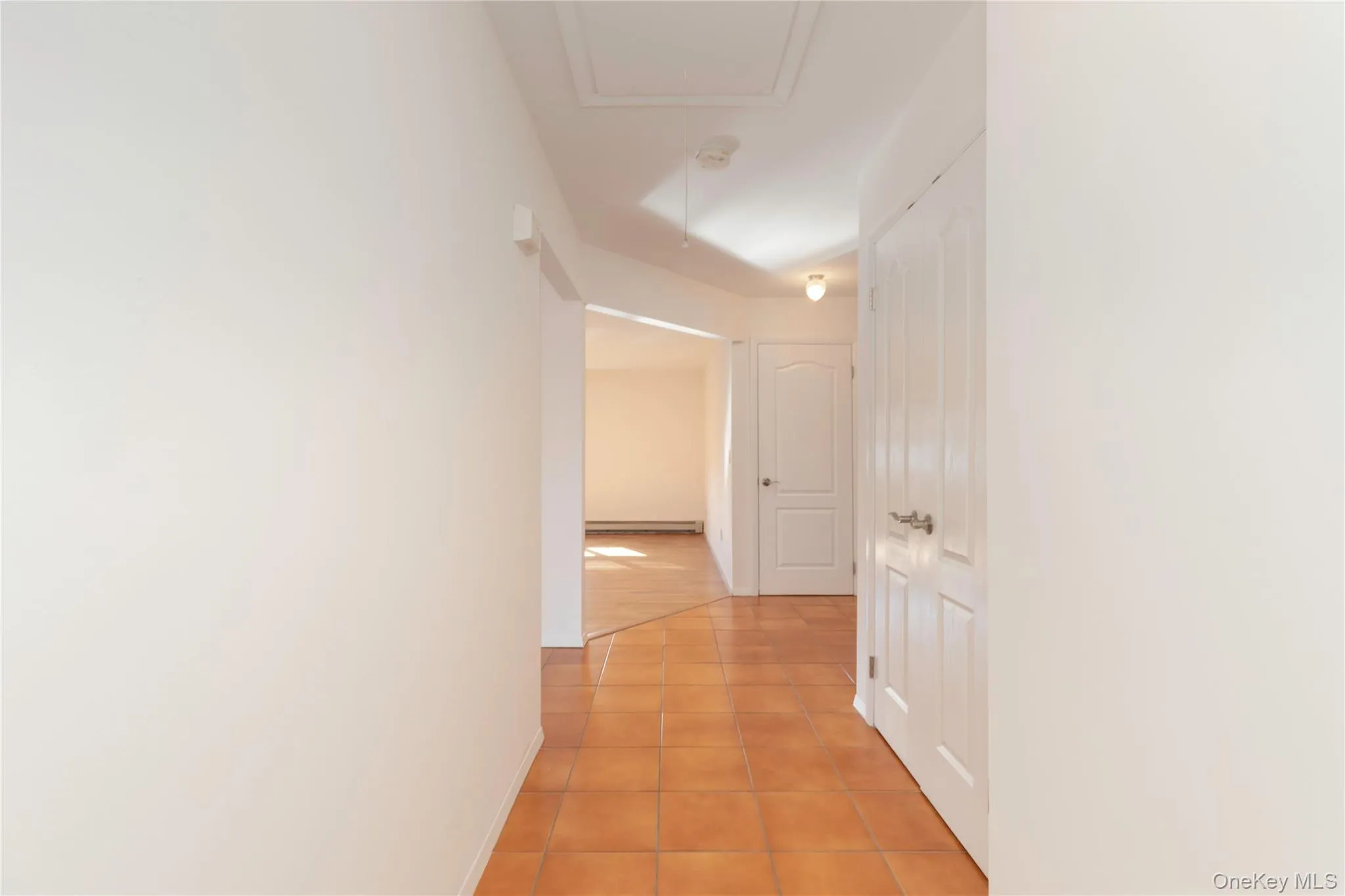 Hallway featuring light tile patterned flooring and baseboards Hallway featuring light tile patterned flooring and baseboards