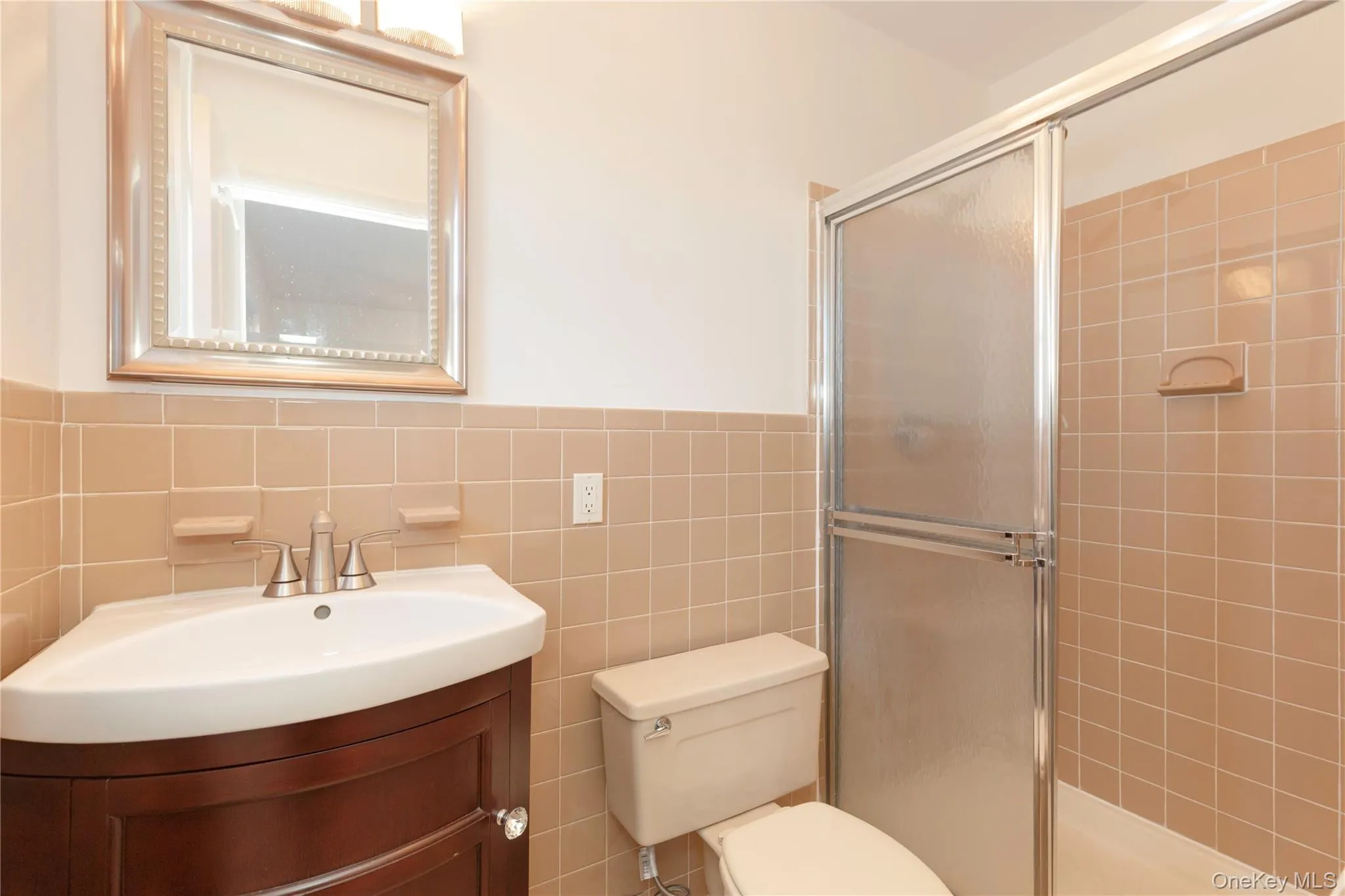 Primary bathroom with tile walls, vanity, a stall shower, and wainscoting Primary bathroom with tile walls, vanity, a stall shower, and wainscoting