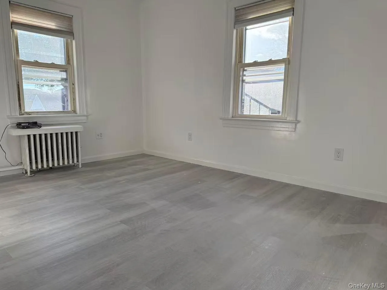 Unfurnished room with radiator and wood finished floors Unfurnished room with radiator and wood finished floors