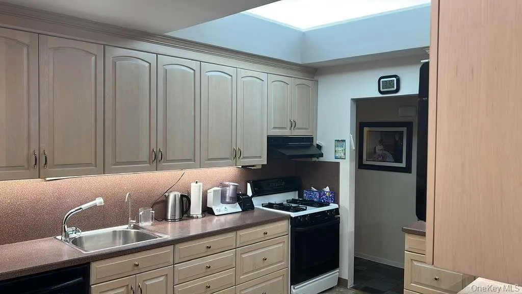 Kitchen with gas range oven, under cabinet range hood, dishwasher, and dark countertops Kitchen with gas range oven, under cabinet range hood, dishwasher, and dark countertops