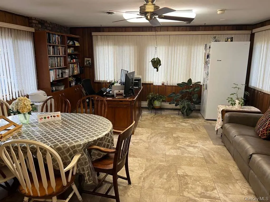 Dining area featuring wooden walls, ceiling fan, and stone finish flooring Dining area featuring wooden walls, ceiling fan, and stone finish flooring