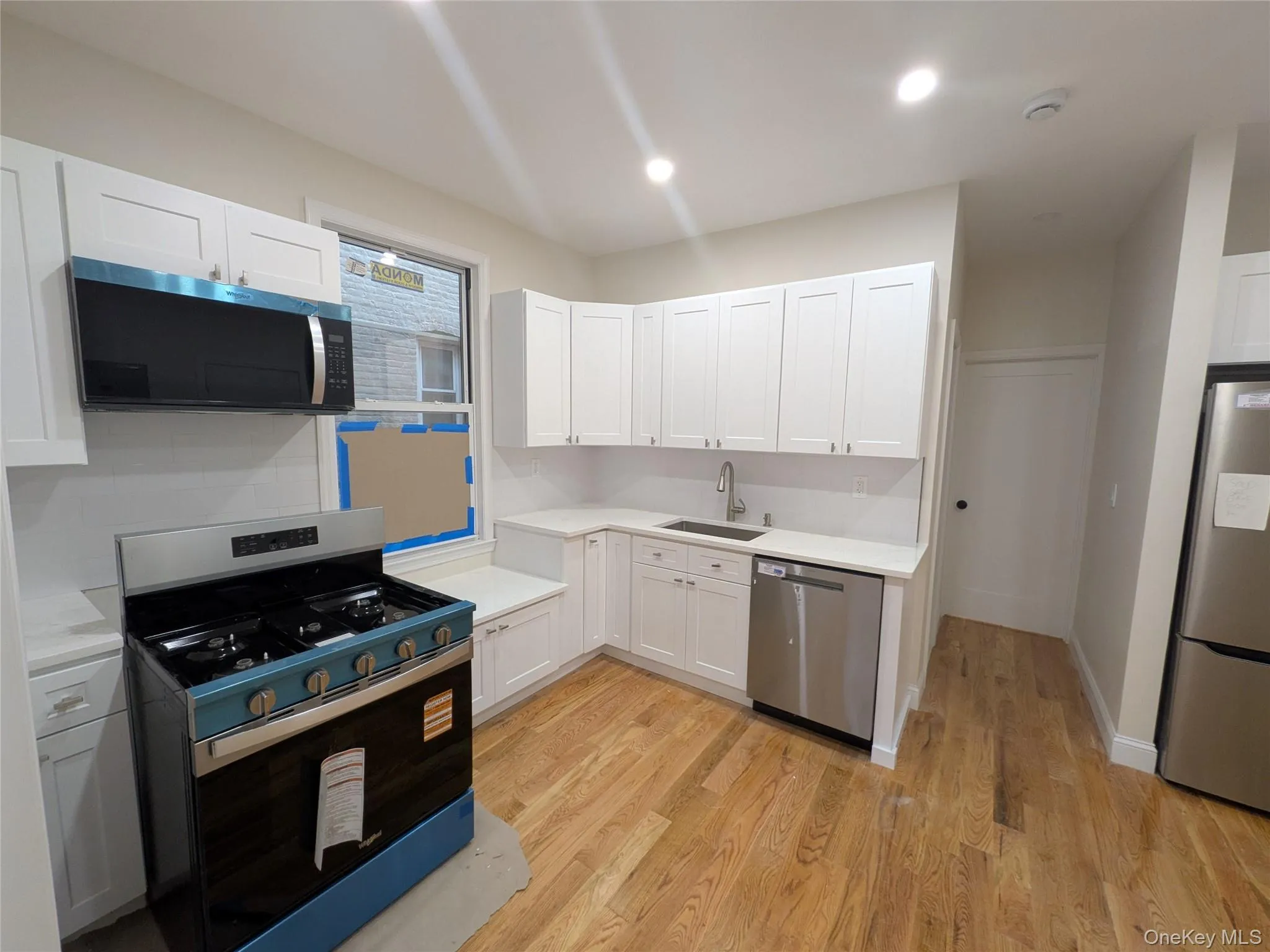 Kitchen featuring appliances with stainless steel finishes, light wood finished floors, white cabinetry, recessed lighting, and backsplash Kitchen featuring appliances with stainless steel finishes, light wood finished floors, white cabinetry, recessed lighting, and backsplash