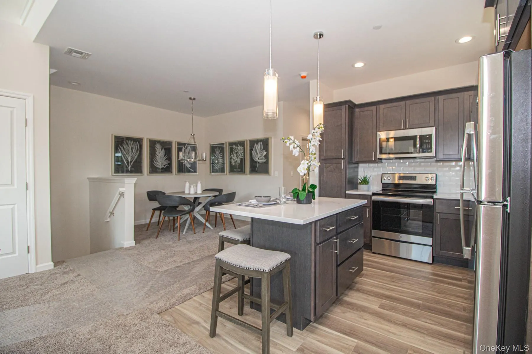 Kitchen featuring appliances with stainless steel finishes, pendant lighting, a breakfast bar, tasteful backsplash, and a center island Kitchen featuring appliances with stainless steel finishes, pendant lighting, a breakfast bar, tasteful backsplash, and a center island
