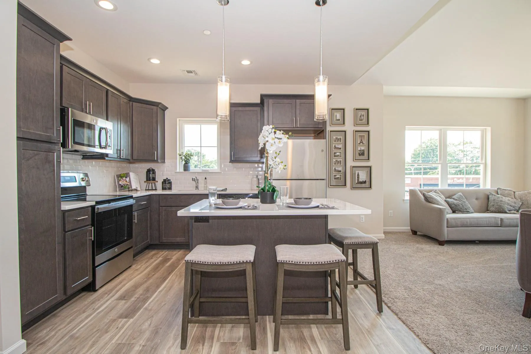 Kitchen with dark brown cabinetry, appliances with stainless steel finishes, a kitchen island, a breakfast bar, and open floor plan Kitchen with dark brown cabinetry, appliances with stainless steel finishes, a kitchen island, a breakfast bar, and open floor plan
