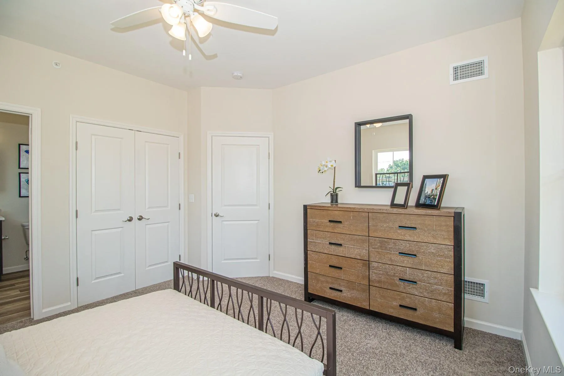 Carpeted bedroom with a closet and a ceiling fan Carpeted bedroom with a closet and a ceiling fan