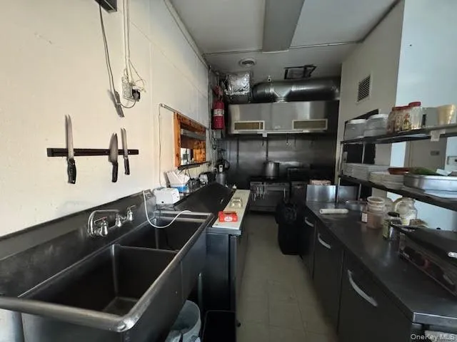 Kitchen featuring dark cabinets, dark countertops, and open shelves Kitchen featuring dark cabinets, dark countertops, and open shelves