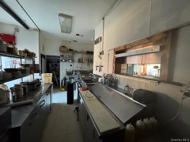 Kitchen with dark cabinets, dark countertops, and light tile patterned flooring Kitchen with dark cabinets, dark countertops, and light tile patterned flooring