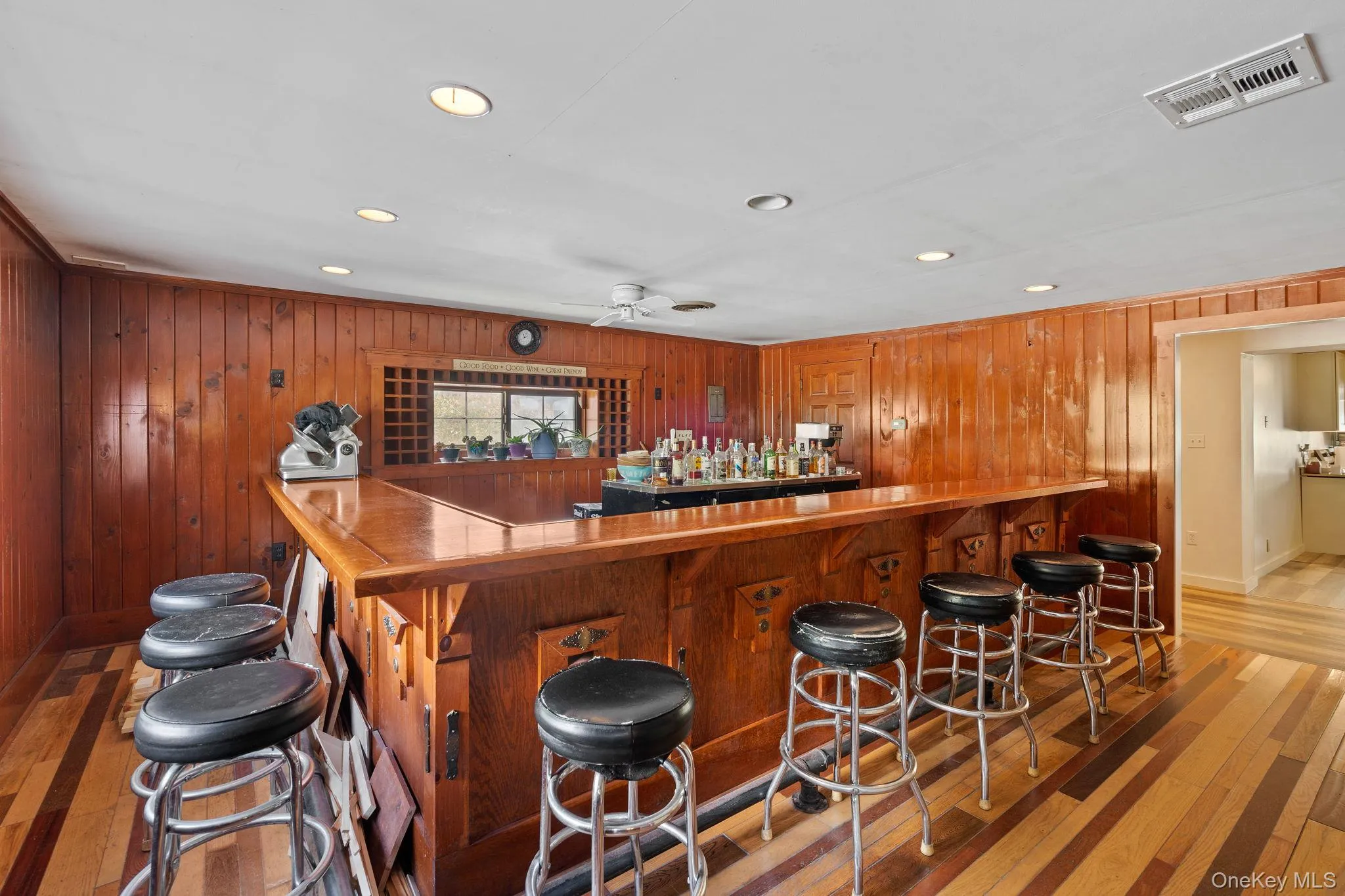 Indoor dry bar with recessed lighting, light wood finished floors, wood walls, and brown cabinets Indoor dry bar with recessed lighting, light wood finished floors, wood walls, and brown cabinets