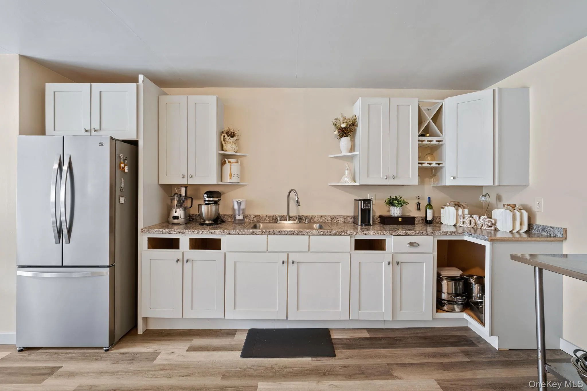 Kitchen featuring open shelves, freestanding refrigerator, white cabinets, and light wood-type flooring Kitchen featuring open shelves, freestanding refrigerator, white cabinets, and light wood-type flooring