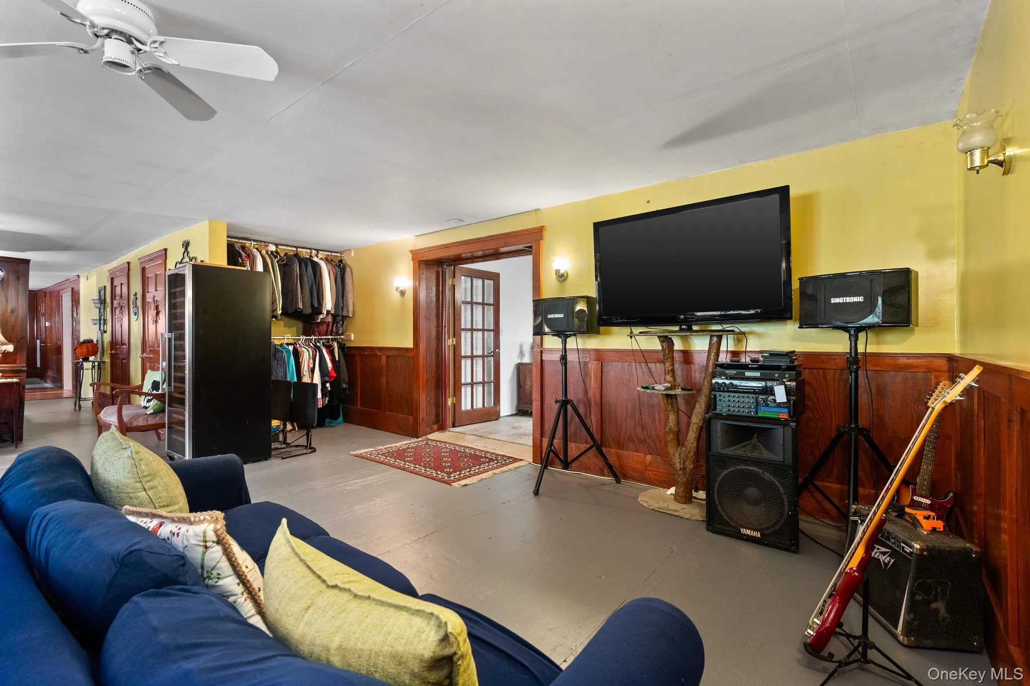 Living area with a wainscoted wall, finished concrete flooring, wood walls, and a ceiling fan Living area with a wainscoted wall, finished concrete flooring, wood walls, and a ceiling fan