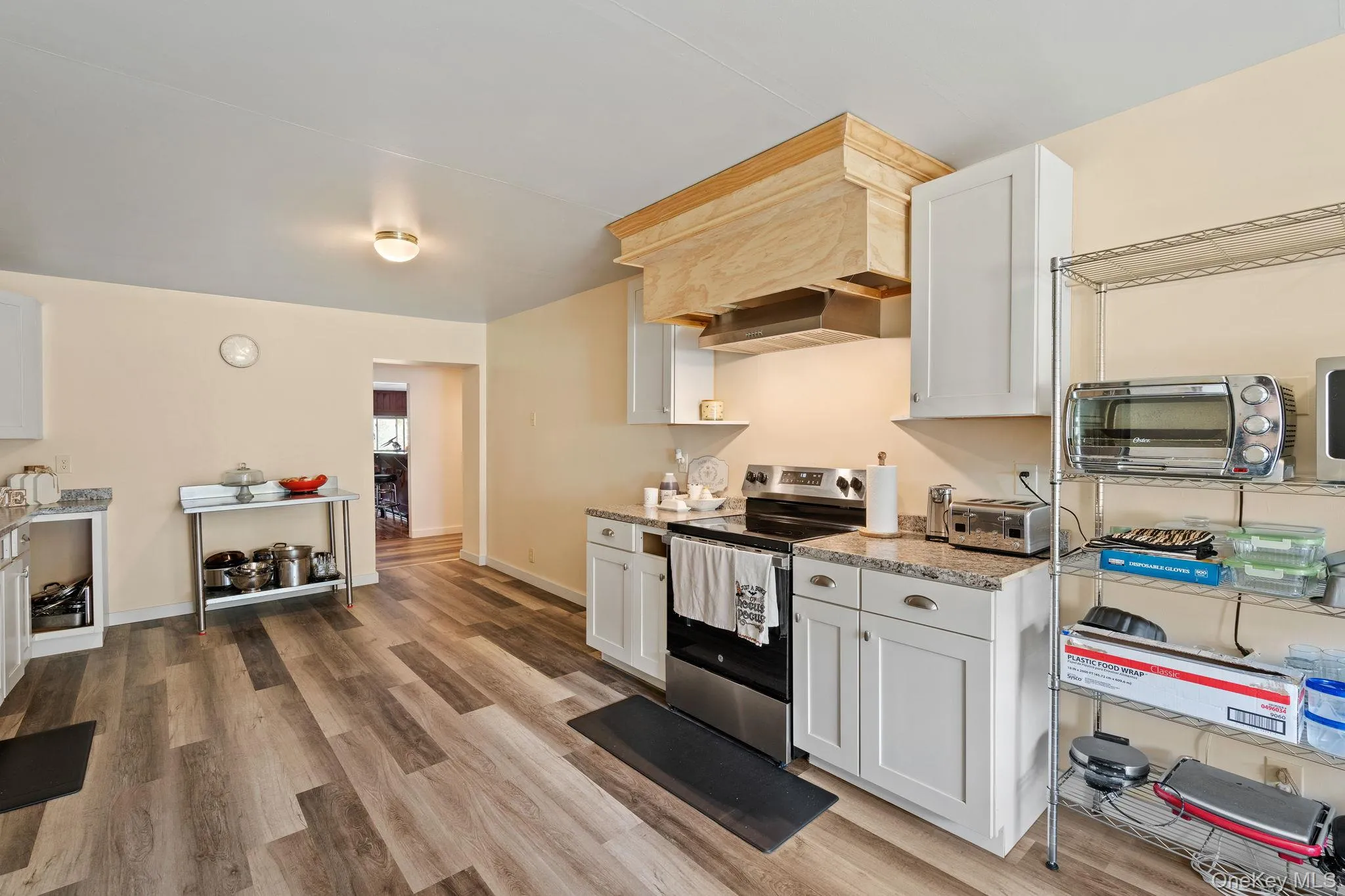 Kitchen with stainless steel electric range oven, white cabinets, and light wood-type flooring Kitchen with stainless steel electric range oven, white cabinets, and light wood-type flooring