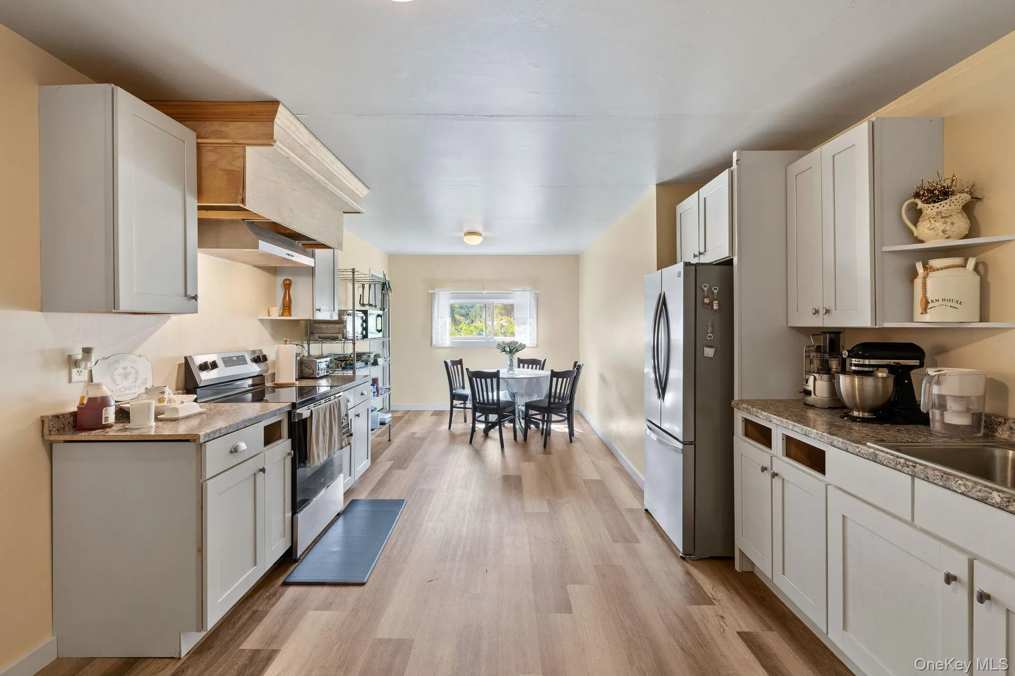 Kitchen featuring open shelves, stainless steel appliances, and white cabinets Kitchen featuring open shelves, stainless steel appliances, and white cabinets