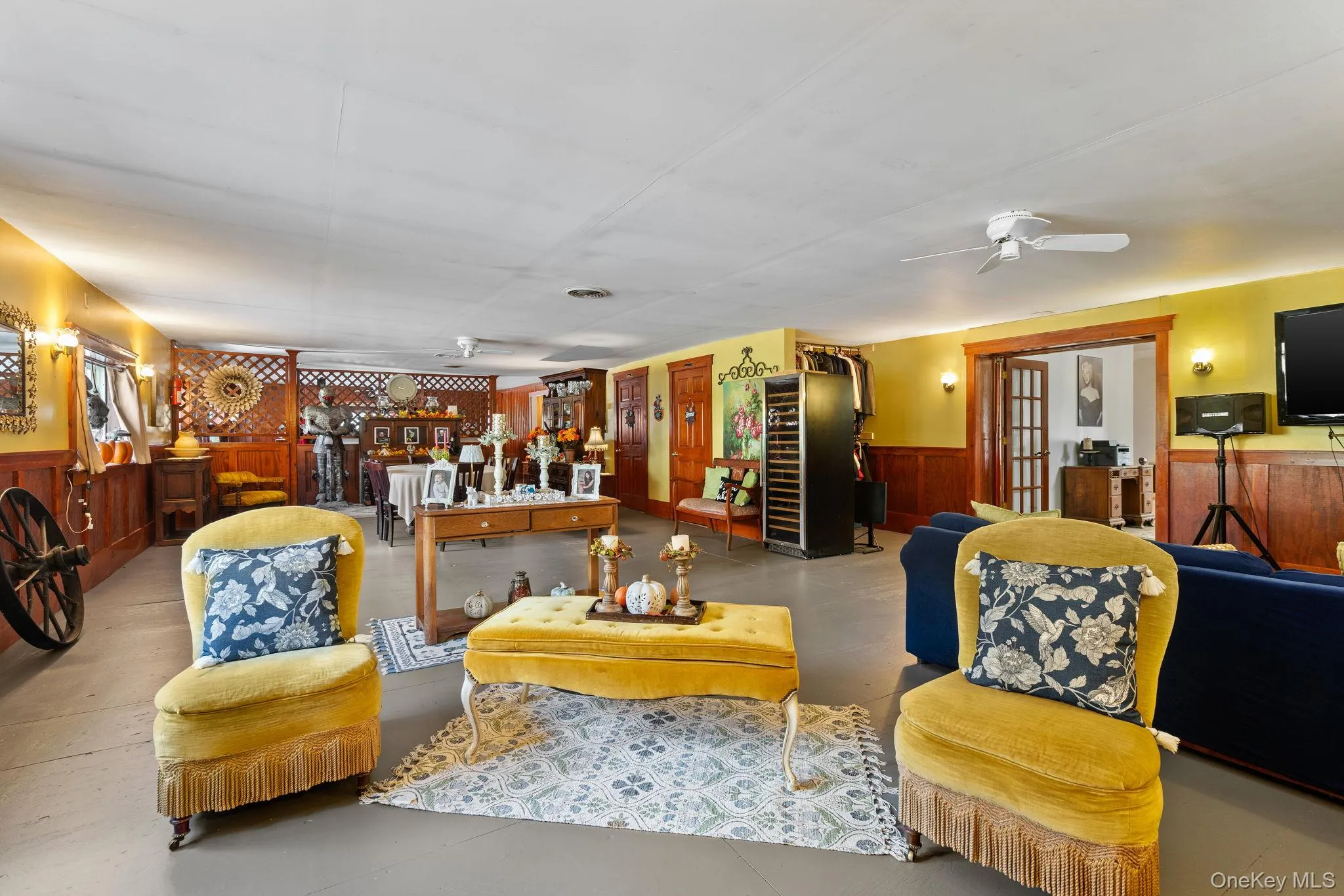 Living area with wainscoting, finished concrete flooring, wooden walls, ceiling fan, and beverage cooler Living area with wainscoting, finished concrete flooring, wooden walls, ceiling fan, and beverage cooler