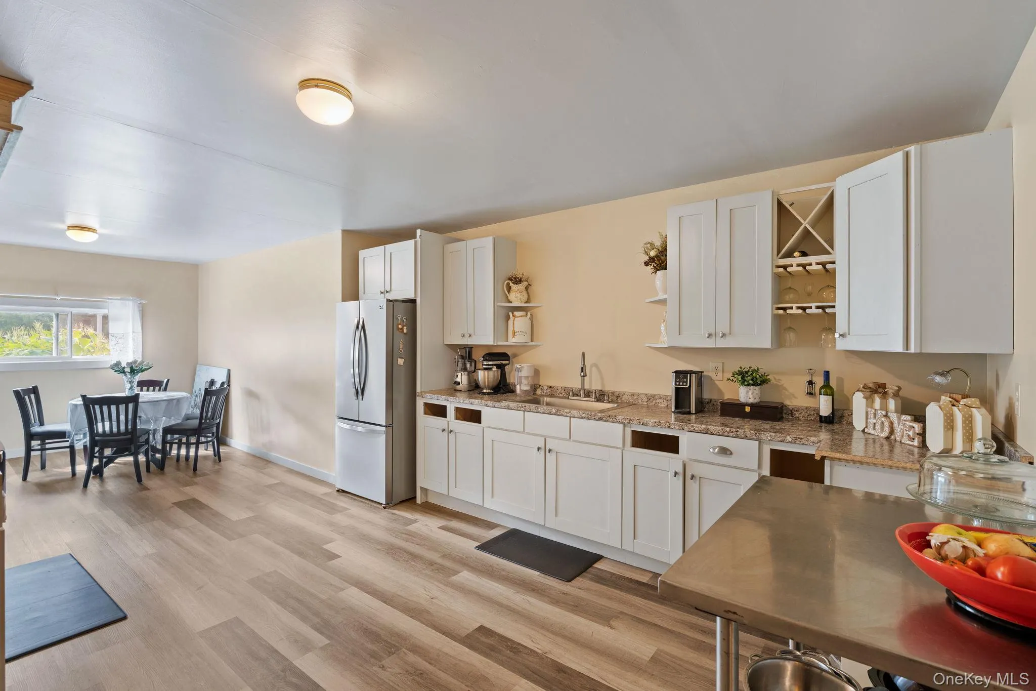 Kitchen featuring open shelves, freestanding refrigerator, light stone counters, light wood finished floors, and white cabinetry Kitchen featuring open shelves, freestanding refrigerator, light stone counters, light wood finished floors, and white cabinetry