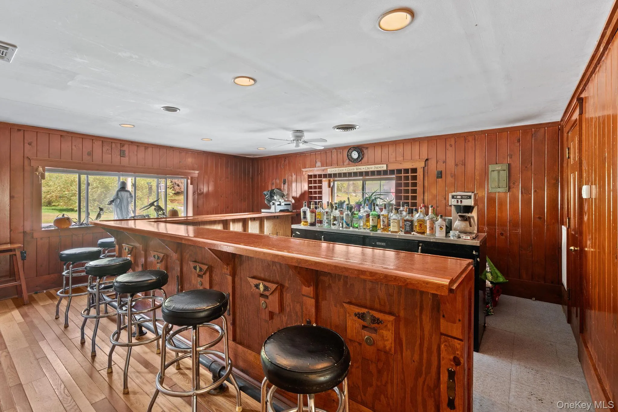 Indoor dry bar featuring wooden walls, recessed lighting, brown cabinets, a ceiling fan, and light countertops Indoor dry bar featuring wooden walls, recessed lighting, brown cabinets, a ceiling fan, and light countertops