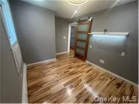 Unfurnished bedroom featuring a barn door and wood finished floors Unfurnished bedroom featuring a barn door and wood finished floors