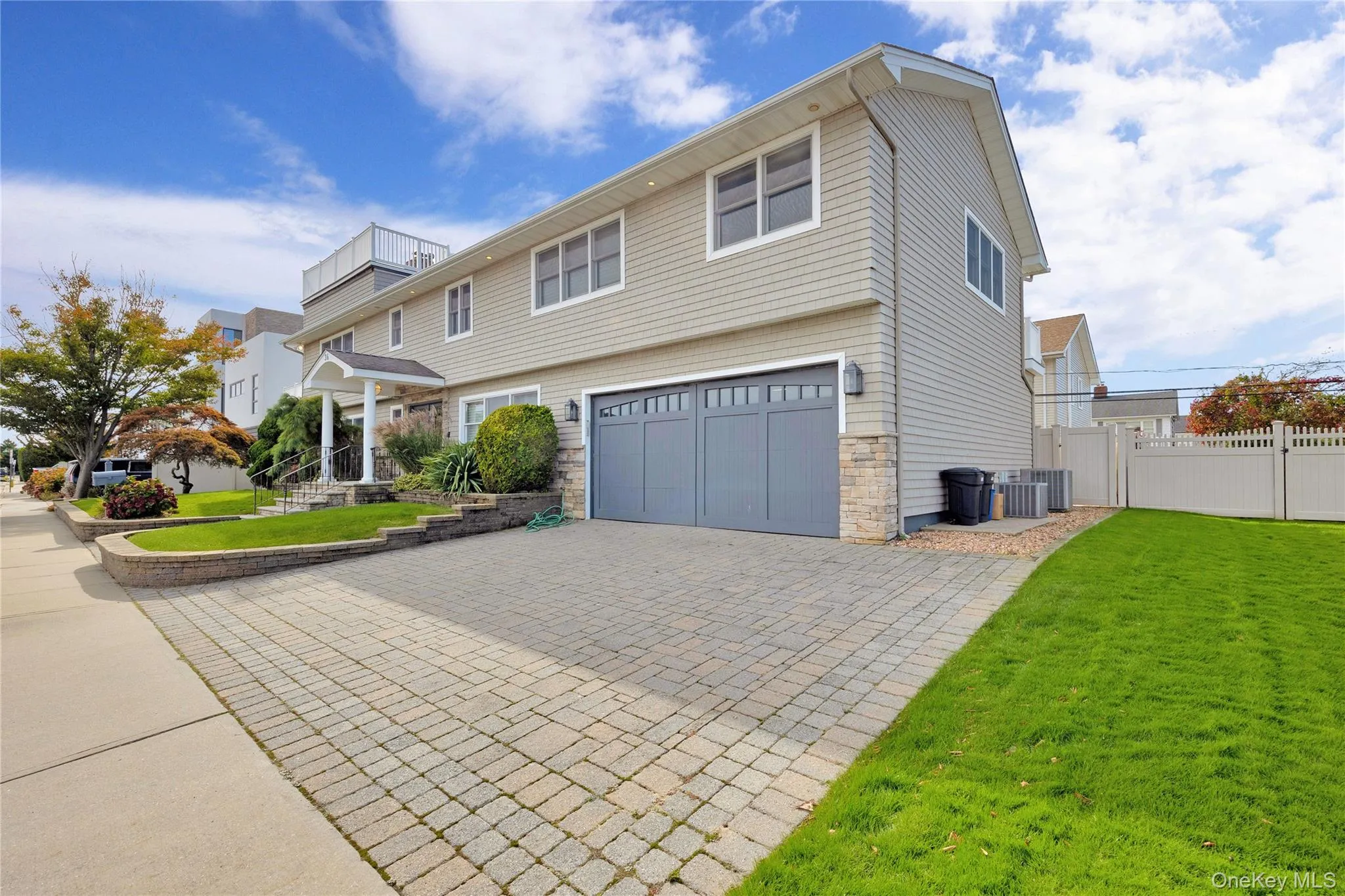 Colonial home with stone siding, decorative driveway, and an attached garage Colonial home with stone siding, decorative driveway, and an attached garage