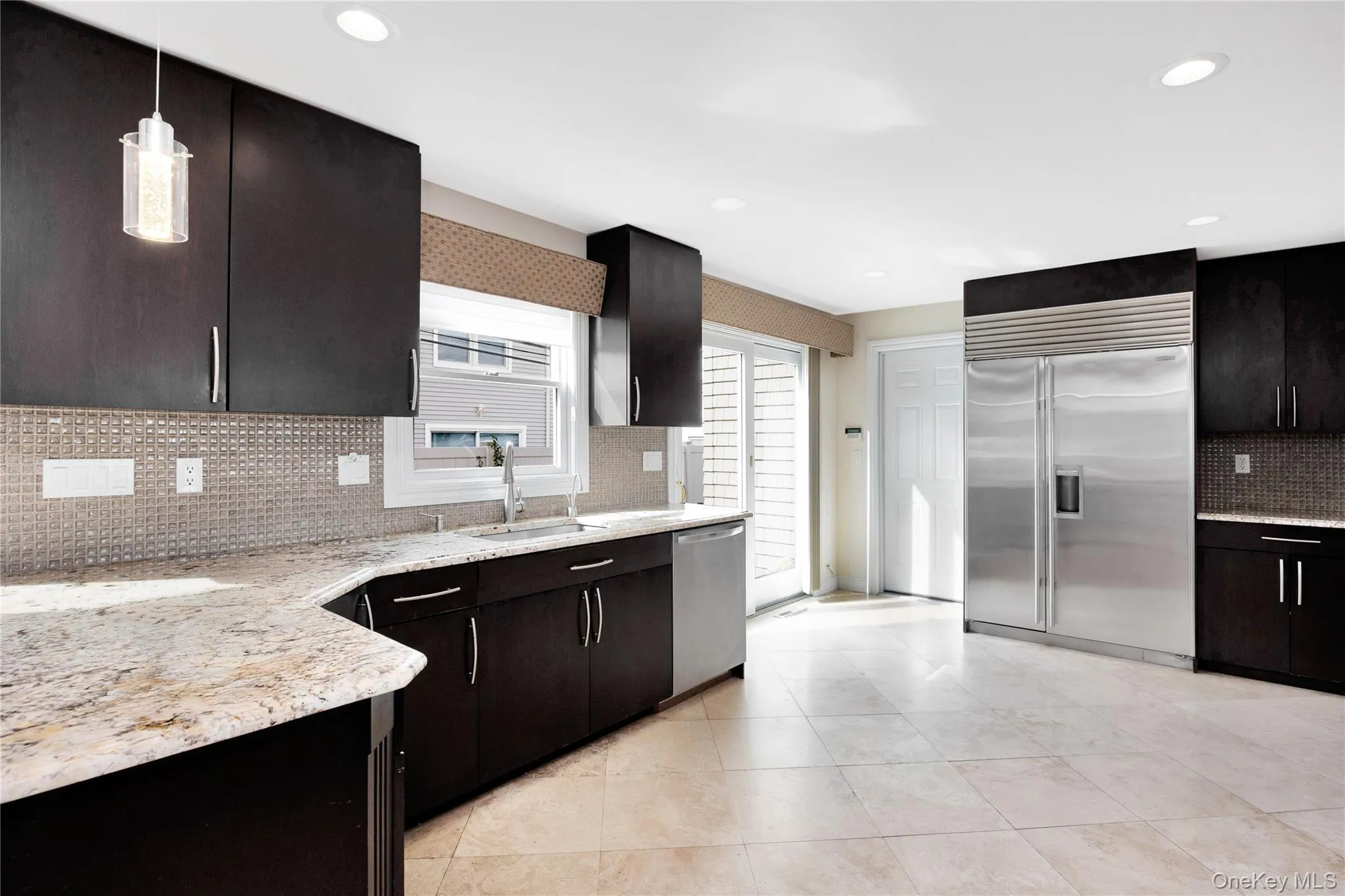 Kitchen with tasteful backsplash, appliances with stainless steel finishes, light tile patterned floors, pendant lighting, and recessed lighting Kitchen with tasteful backsplash, appliances with stainless steel finishes, light tile patterned floors, pendant lighting, and recessed lighting