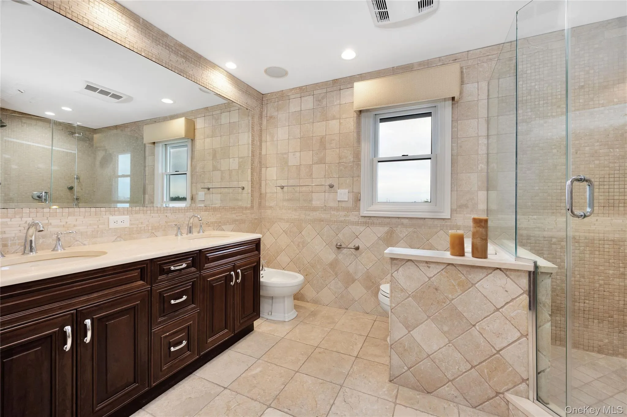 Full bath featuring a stall shower, tile walls, double vanity, light tile patterned flooring, and beam ceiling Full bath featuring a stall shower, tile walls, double vanity, light tile patterned flooring, and beam ceiling