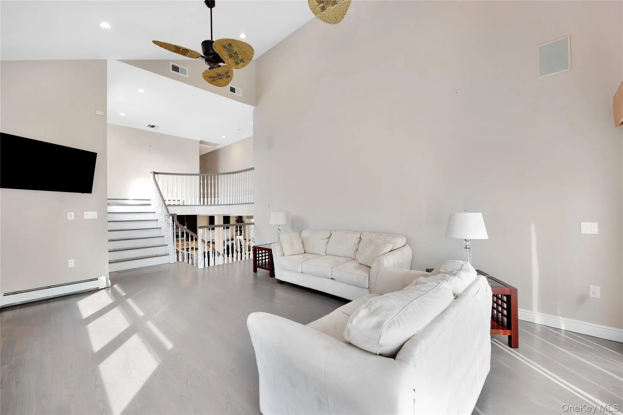 Living area featuring high vaulted ceiling, a baseboard radiator, light wood finished floors, recessed lighting, and a ceiling fan Living area featuring high vaulted ceiling, a baseboard radiator, light wood finished floors, recessed lighting, and a ceiling fan