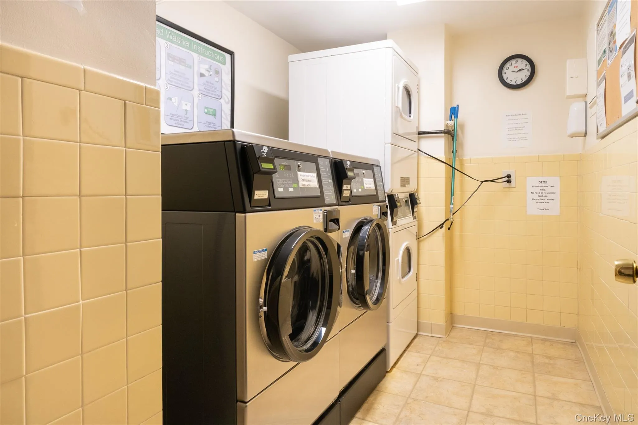 Communal laundry room featuring estacked washer and dryer, tile walls, and washer and clothes dryer Communal laundry room featuring estacked washer and dryer, tile walls, and washer and clothes dryer