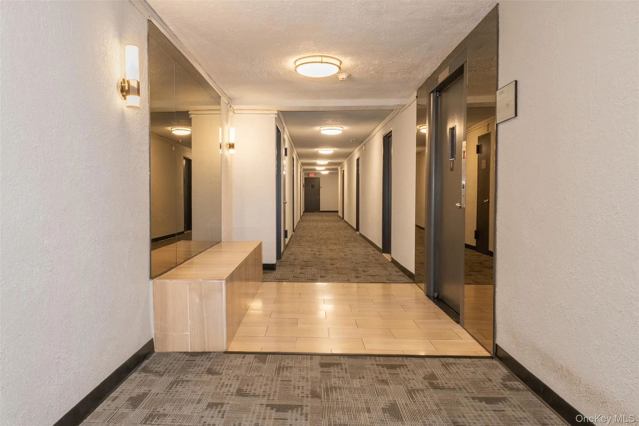 Hall featuring a textured wall, a textured ceiling, and wood tiled floors Hall featuring a textured wall, a textured ceiling, and wood tiled floors
