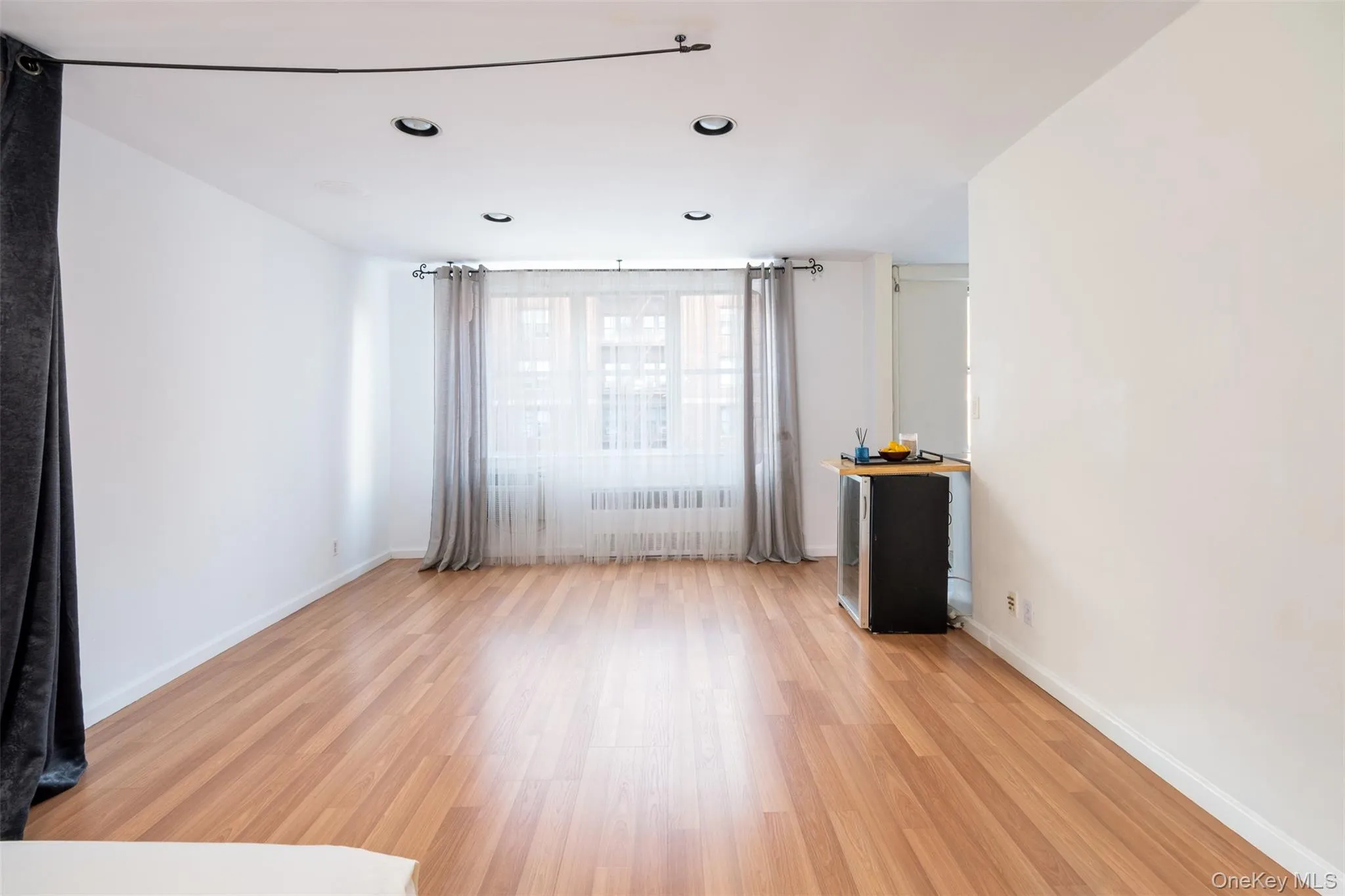 Empty room with radiator heating unit, light wood-type flooring, and recessed lighting Empty room with radiator heating unit, light wood-type flooring, and recessed lighting