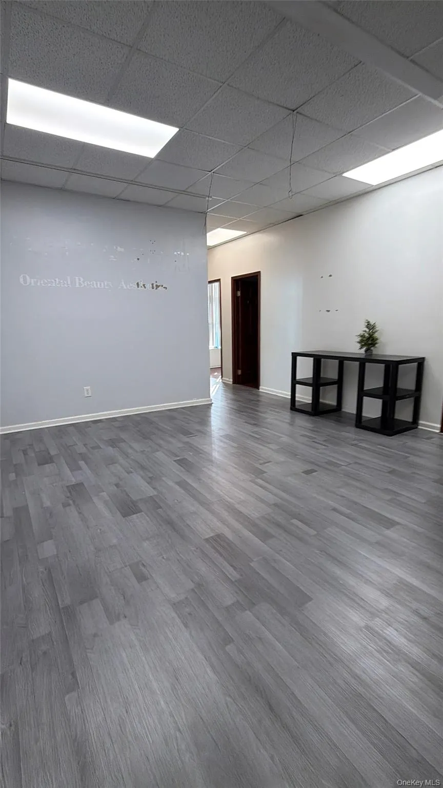 Spare room featuring wood finished floors and a paneled ceiling Spare room featuring wood finished floors and a paneled ceiling