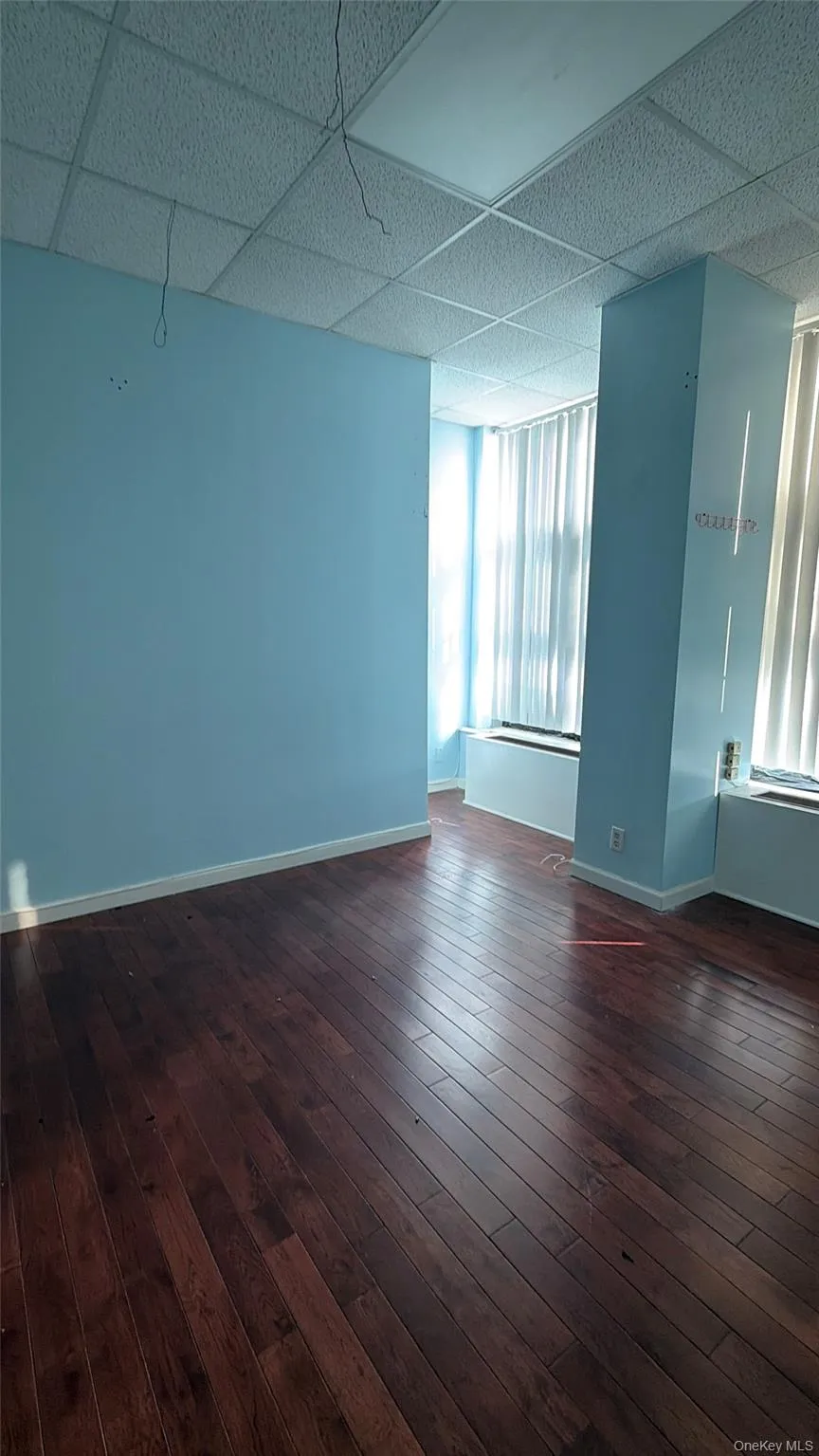 Spare room with a drop ceiling and dark wood finished floors Spare room with a drop ceiling and dark wood finished floors