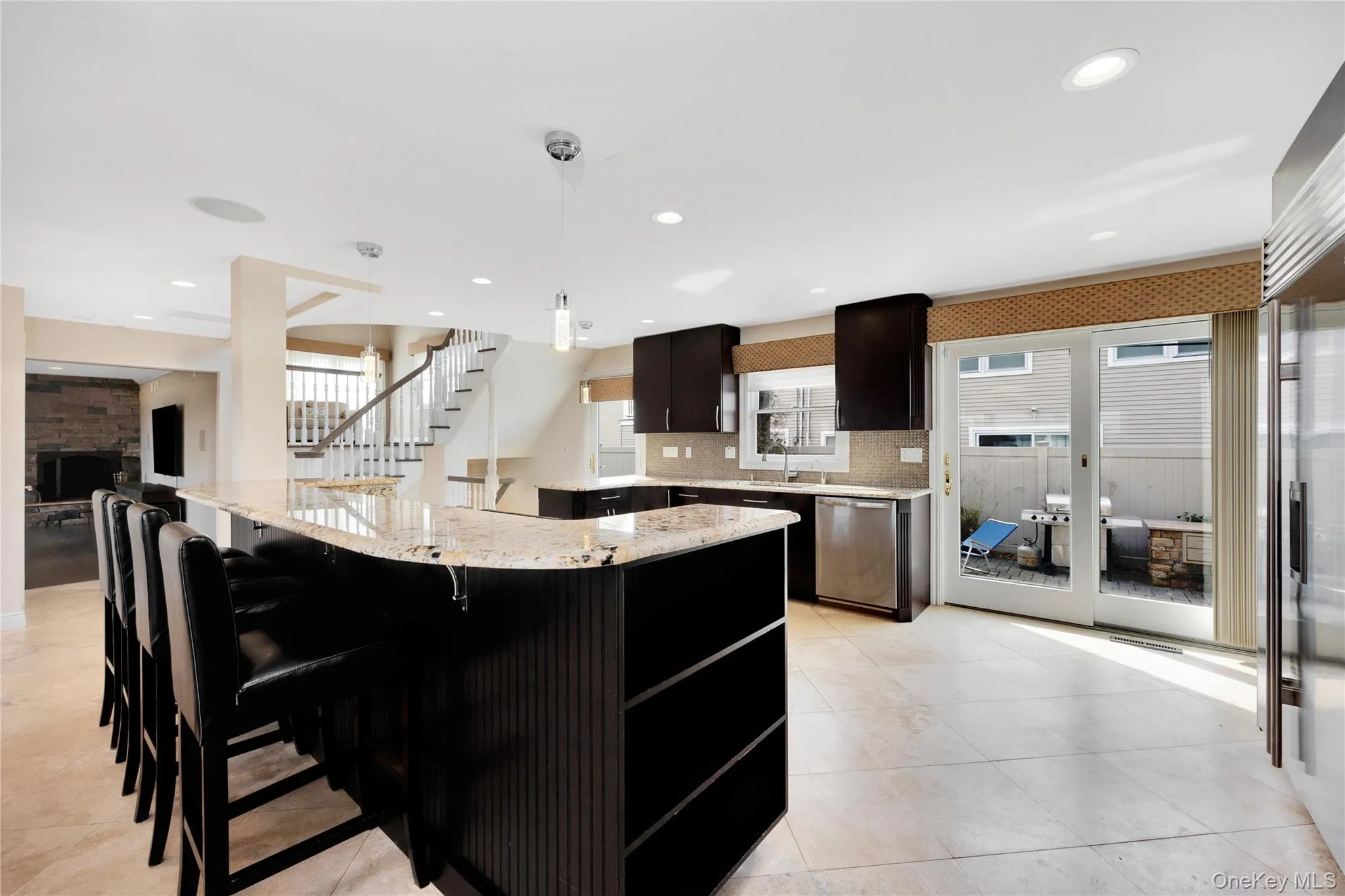 Kitchen featuring light stone counters, healthy amount of natural light, tasteful backsplash, a large island, and recessed lighting Kitchen featuring light stone counters, healthy amount of natural light, tasteful backsplash, a large island, and recessed lighting