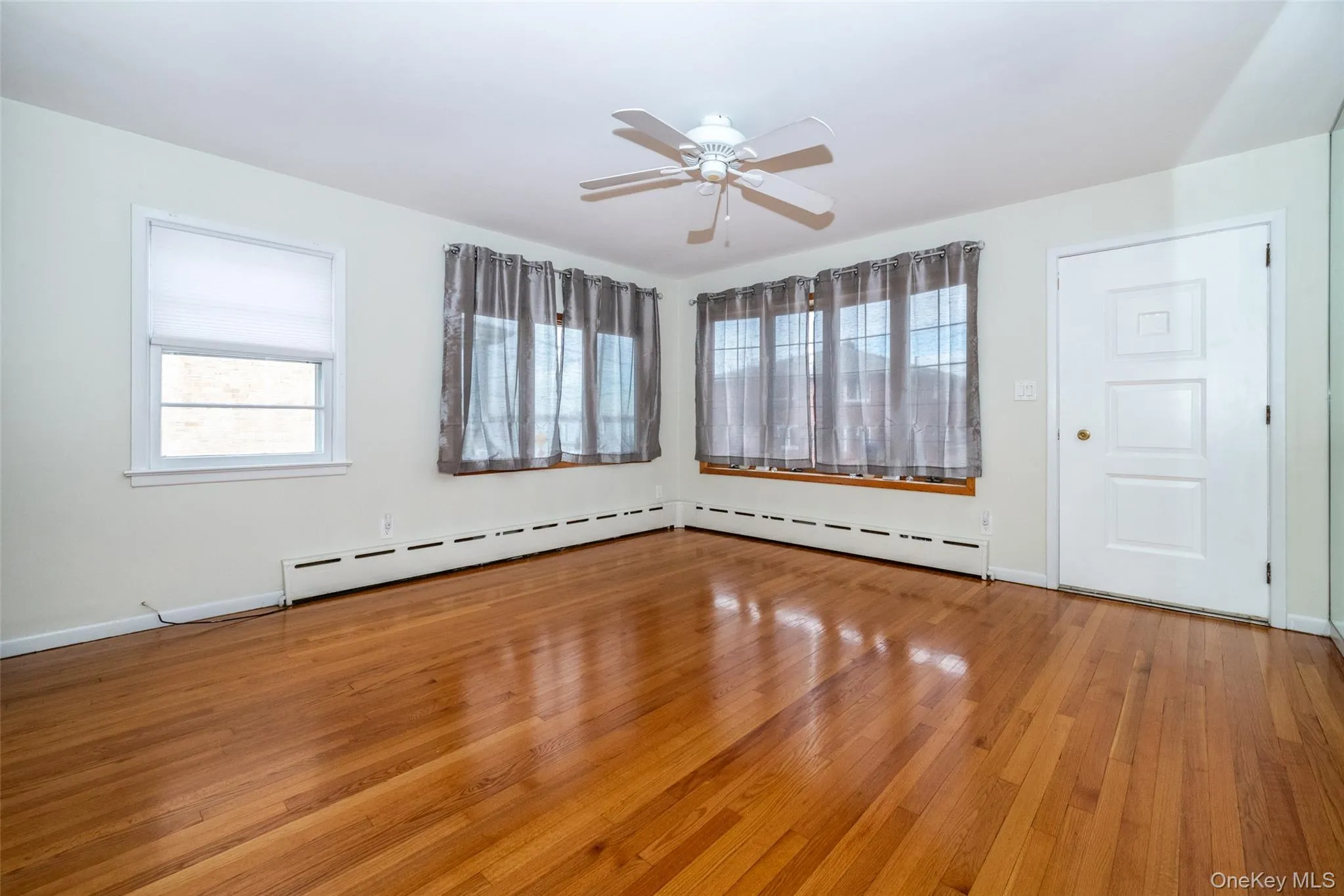 Spare room featuring light wood-type flooring, a ceiling fan, and baseboard heating Spare room featuring light wood-type flooring, a ceiling fan, and baseboard heating