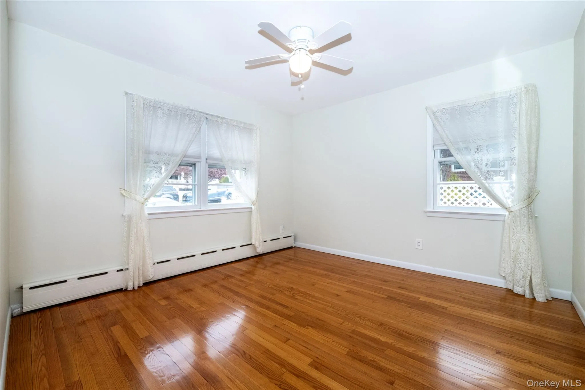 Spare room featuring a baseboard radiator, wood-type flooring, and plenty of natural light Spare room featuring a baseboard radiator, wood-type flooring, and plenty of natural light
