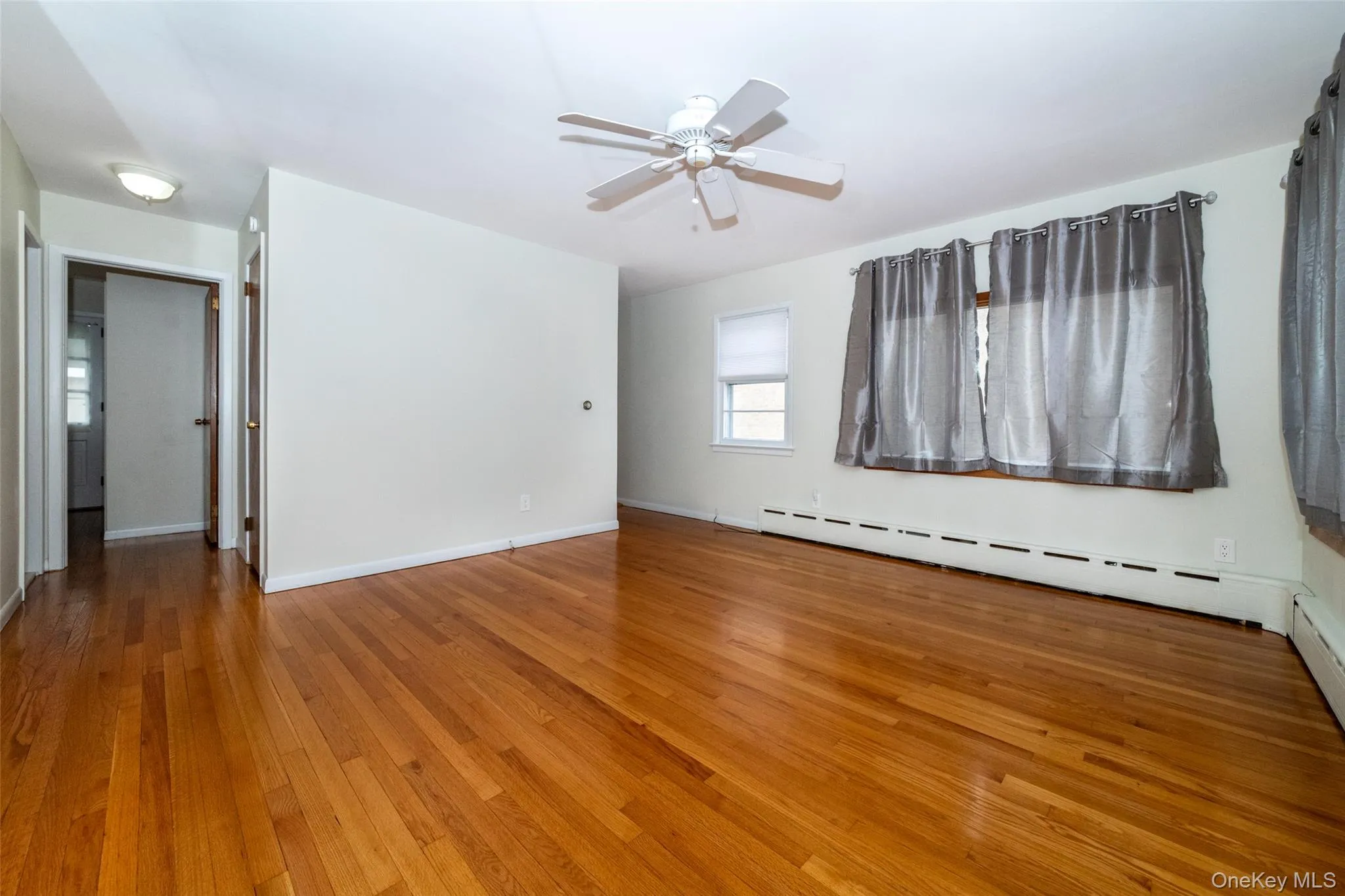 Spare room with light wood finished floors, a baseboard heating unit, and ceiling fan Spare room with light wood finished floors, a baseboard heating unit, and ceiling fan