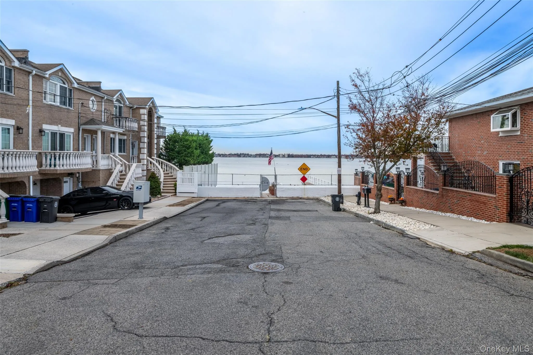 View of street featuring a water view, sidewalks, curbs, stairs, and traffic signs View of street featuring a water view, sidewalks, curbs, stairs, and traffic signs