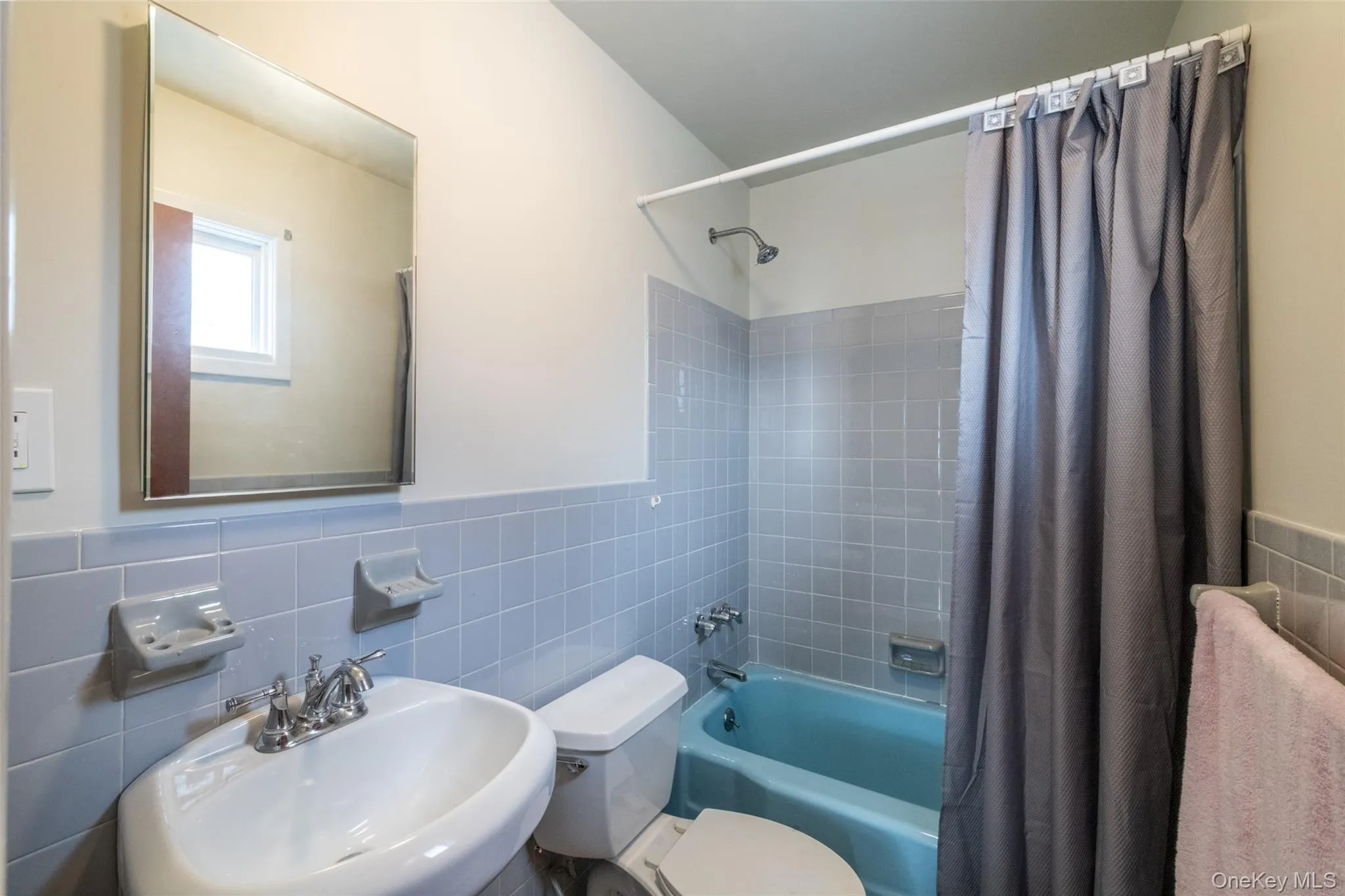 Bathroom with shower / bath combination with curtain, tile walls, and a wainscoted wall Bathroom with shower / bath combination with curtain, tile walls, and a wainscoted wall