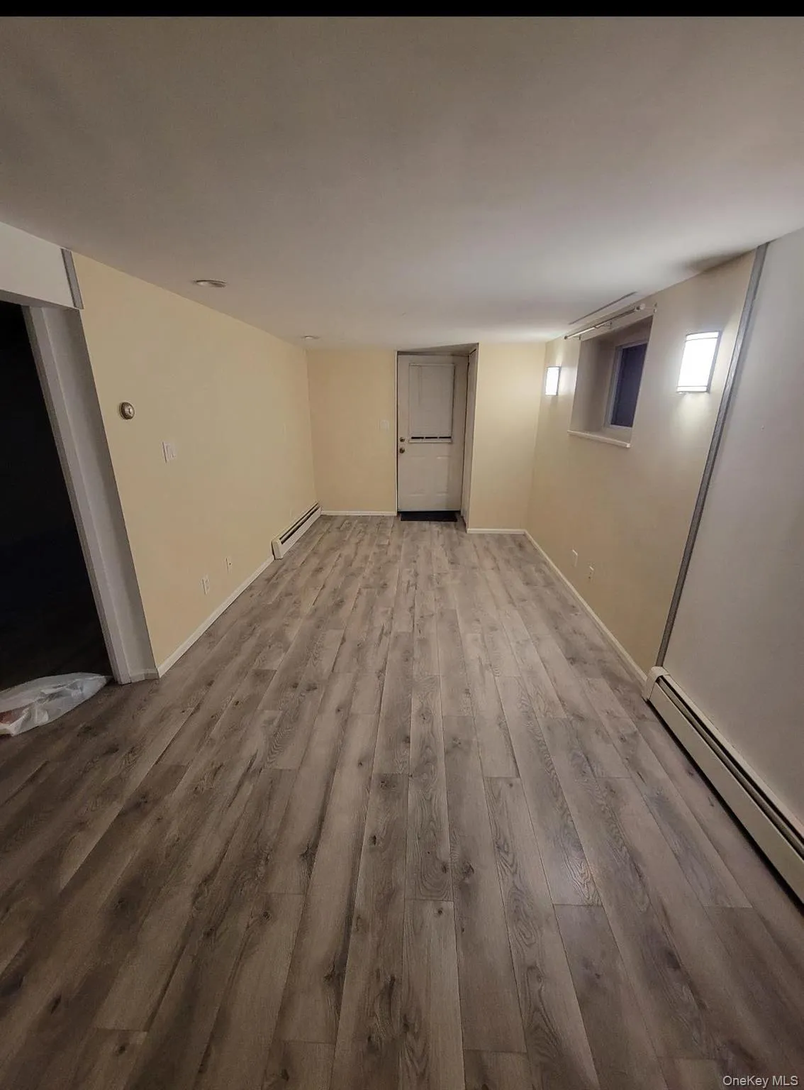 Basement with a baseboard heating unit and wood finished floors Basement with a baseboard heating unit and wood finished floors