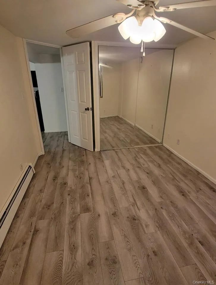 Unfurnished bedroom featuring baseboard heating, light wood finished floors, a ceiling fan, and a closet Unfurnished bedroom featuring baseboard heating, light wood finished floors, a ceiling fan, and a closet