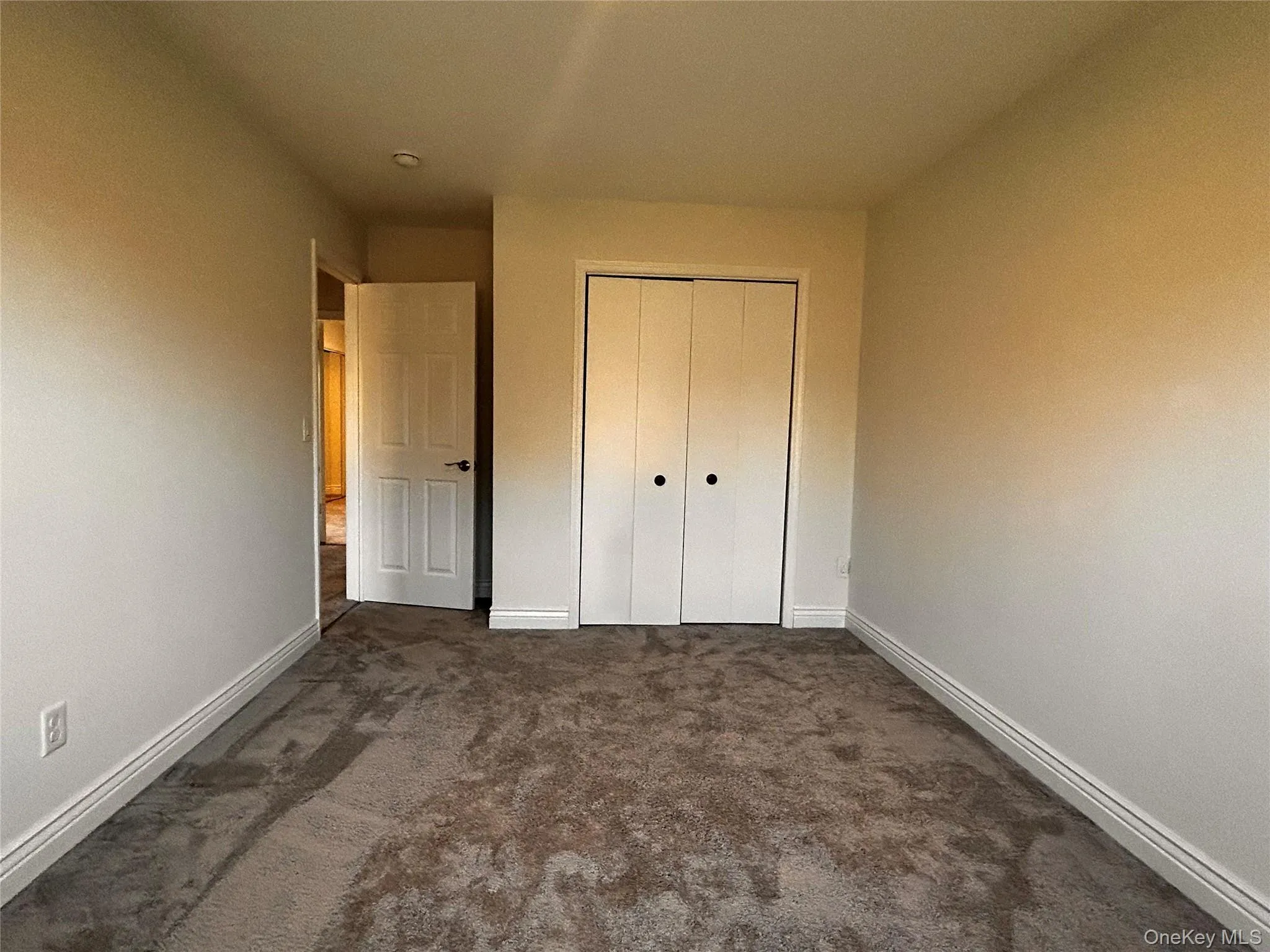 Unfurnished bedroom featuring dark colored carpet and a closet Unfurnished bedroom featuring dark colored carpet and a closet